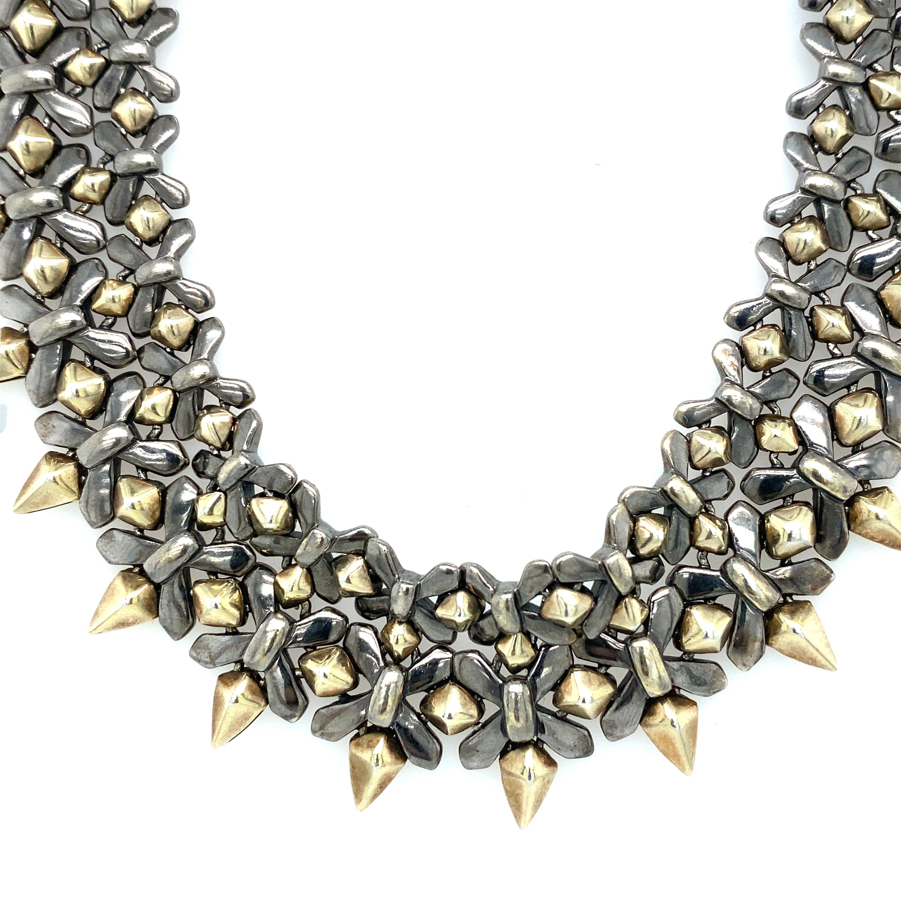 Item Details: This collar necklace by Stephen Webster is part of the designer's Superstud collection. It features a woven stud design, making this choker necklace a flexible and versatile statement piece. The studded dangles are toned in gold. This