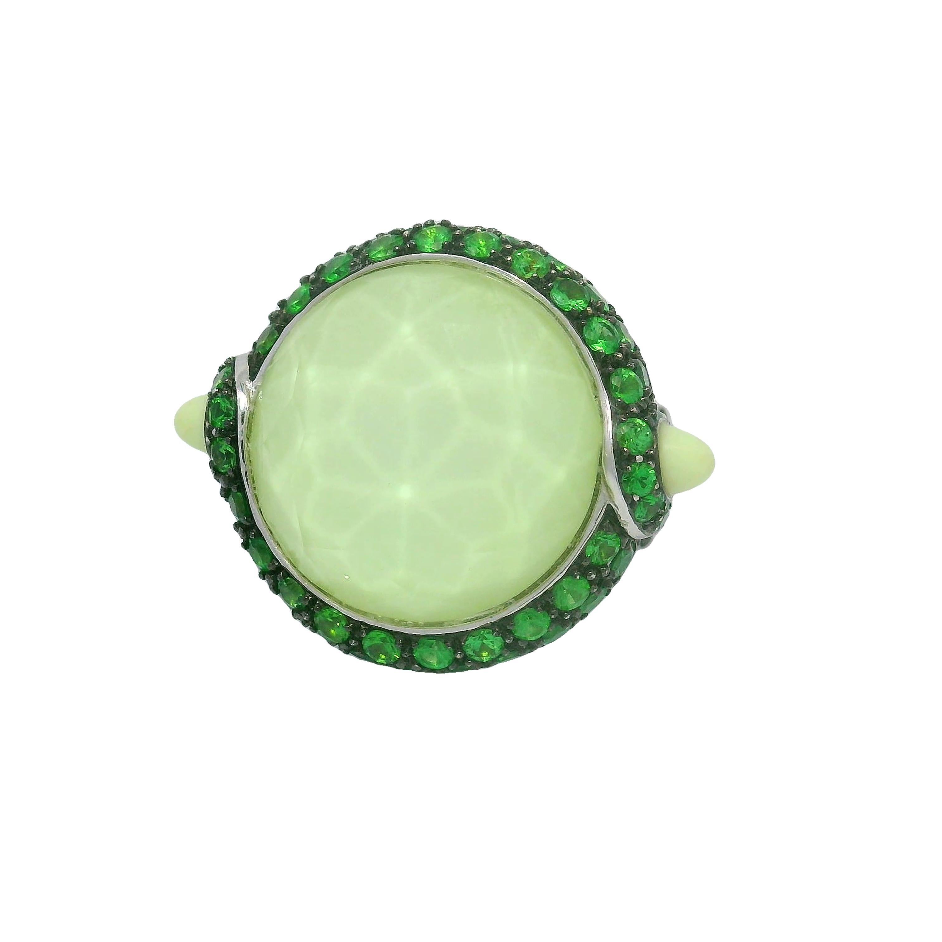 Une bague saisissante dont la pièce maîtresse est un quartz incolore taillé en rose, dégageant une élégance subtile. Autour de la pierre principale, des grenats tsavorites d'un vert vibrant ajoutent un contraste et un éclat vifs. Réalisée en or 18