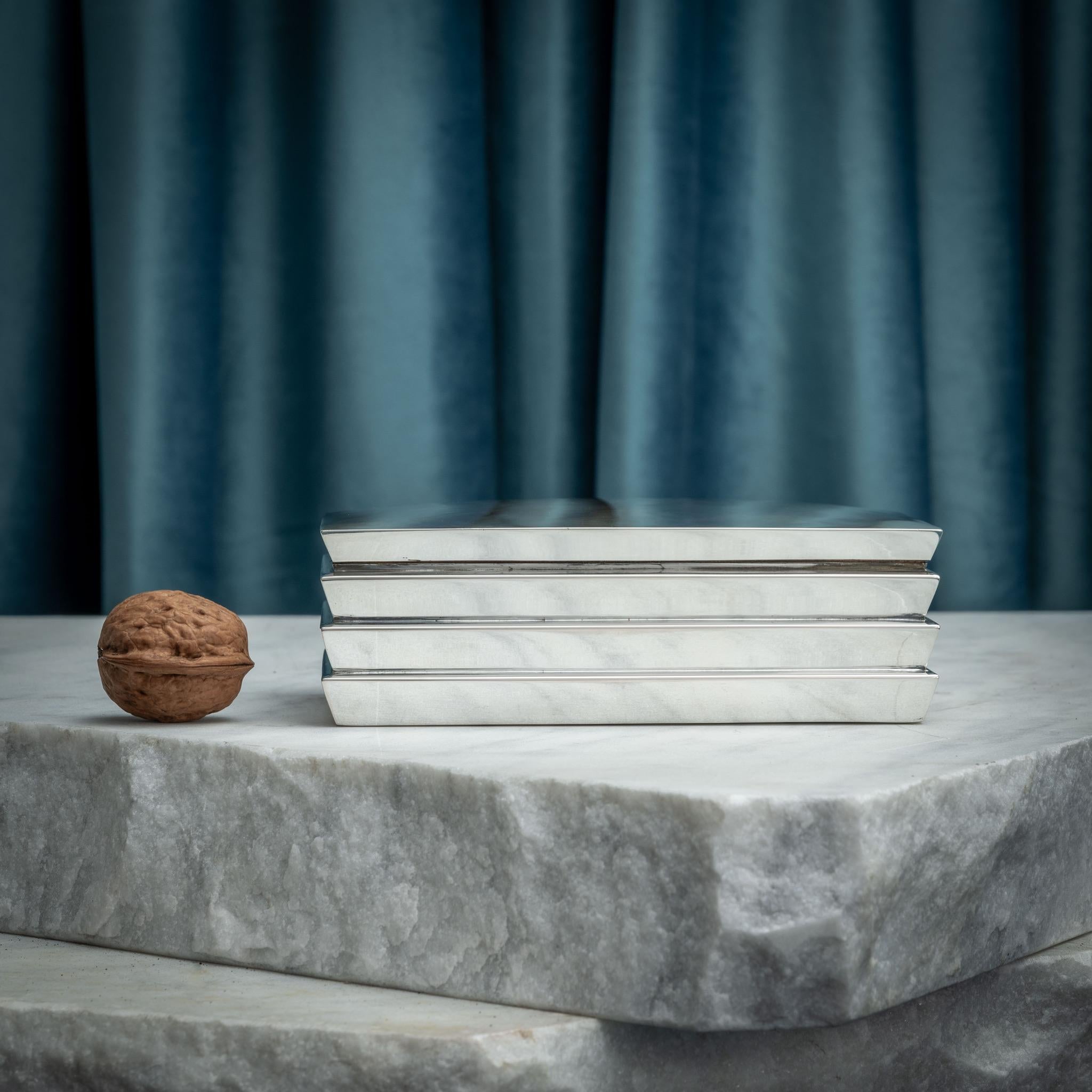 Boîte en argent avec un design inhabituel en escalier par les orfèvres Hermann Bauer, vers 1930.

Elle porte les marques d'argent de la couronne impériale et du croissant de lune pour l'Allemagne, ainsi qu'un poinçon de pureté de l'argent de 800.