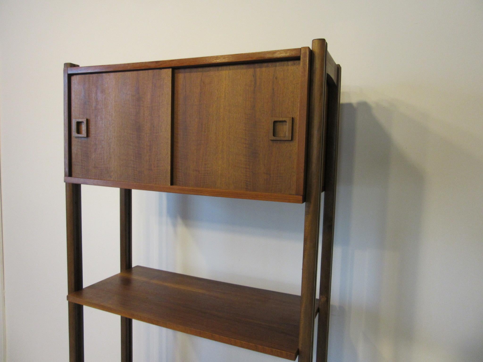 A walnut wall unit with upper two door storage cabinet, middle shelve for your stereo receiver and other equipment and lower area for the turntable and a record cabinet having five slots sits at the base. All the pieces are adjustable so you can