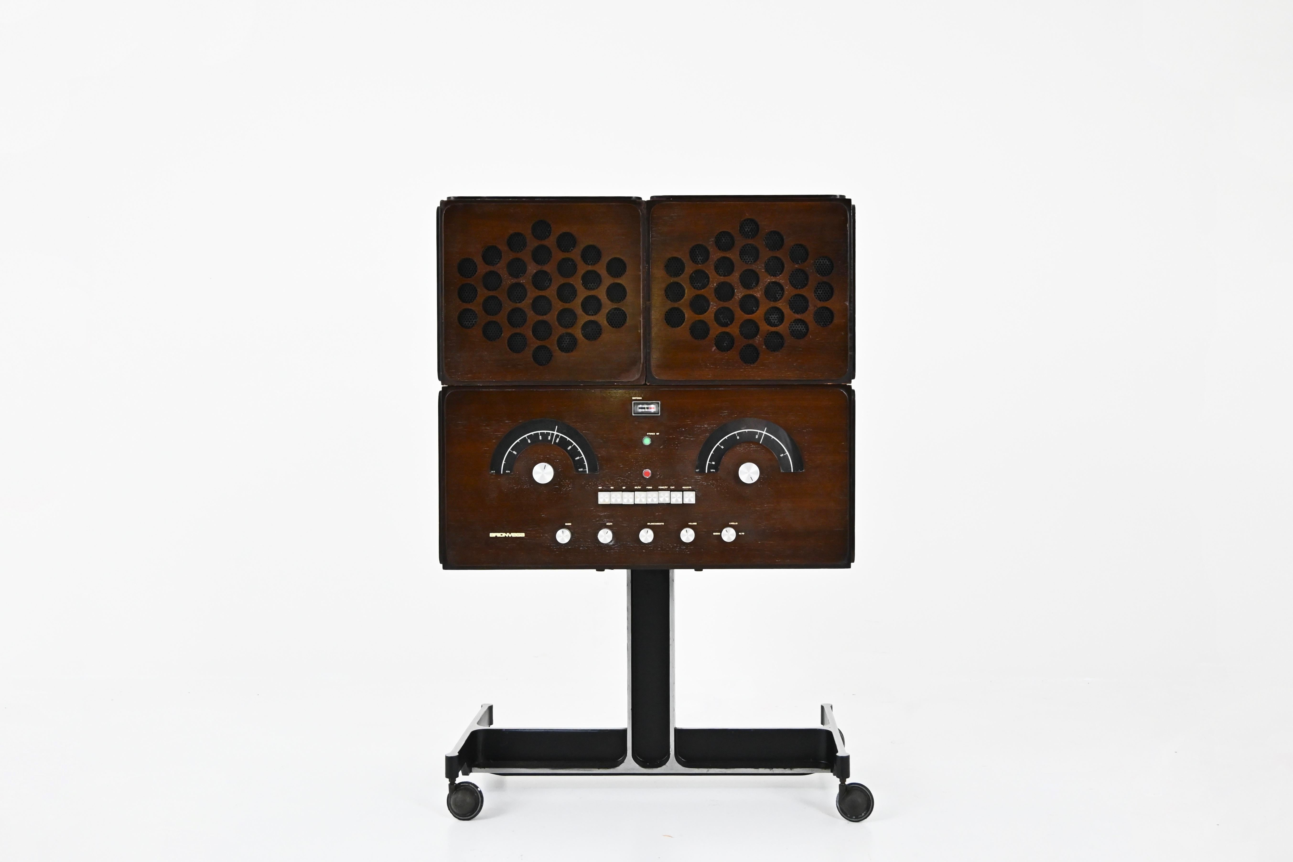 Radio stéréo couleur bois Brionvega. La radio et le tourne-disque fonctionnent parfaitement, il a été entièrement révisé. Il y a une connexion bluethoot pour le GSM. Dimensions en position fermée : hauteur 92 cm, largeur 62 cm, profondeur 37 cm.