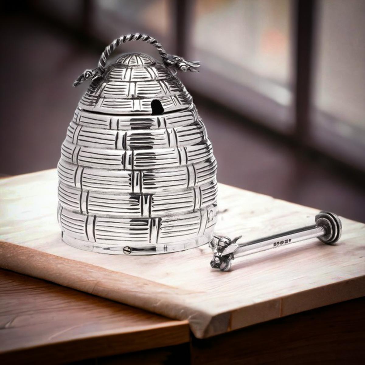 Sterling 925 silver beehive honey pot with a spoon. 
Made in 2022, spoon made in 2021. 

The beehive honey pot, adorned with decorative bees, features two base holes for smooth honey flow and comes with a lid and handle. Although the glass part is