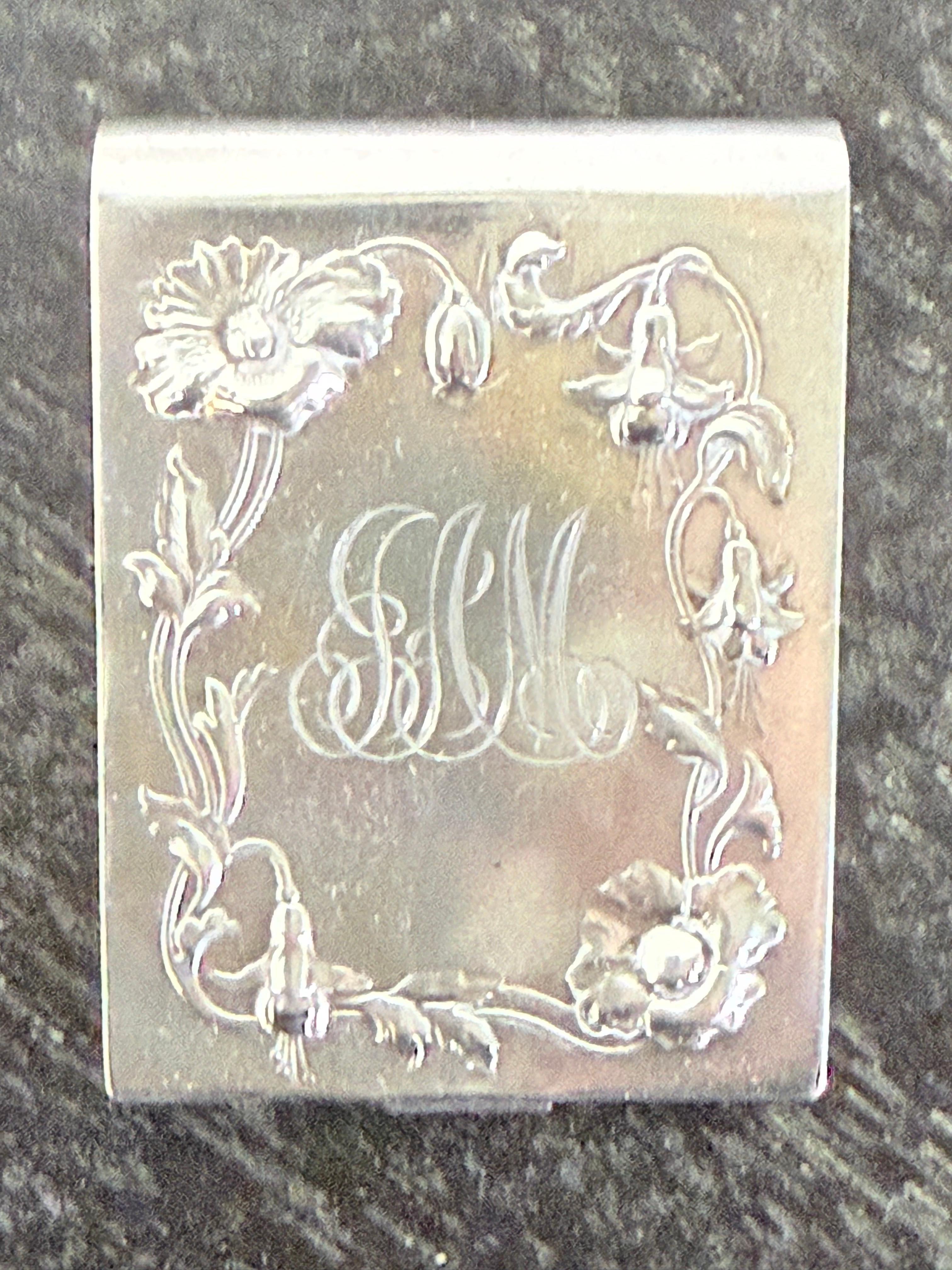 This antique sterling silver match safe, also known as a vesta case, is a finely crafted example of Art Nouveau design dating to the late 19th or early 20th century. The front is beautifully adorned with high-relief floral motifs—likely poppies or
