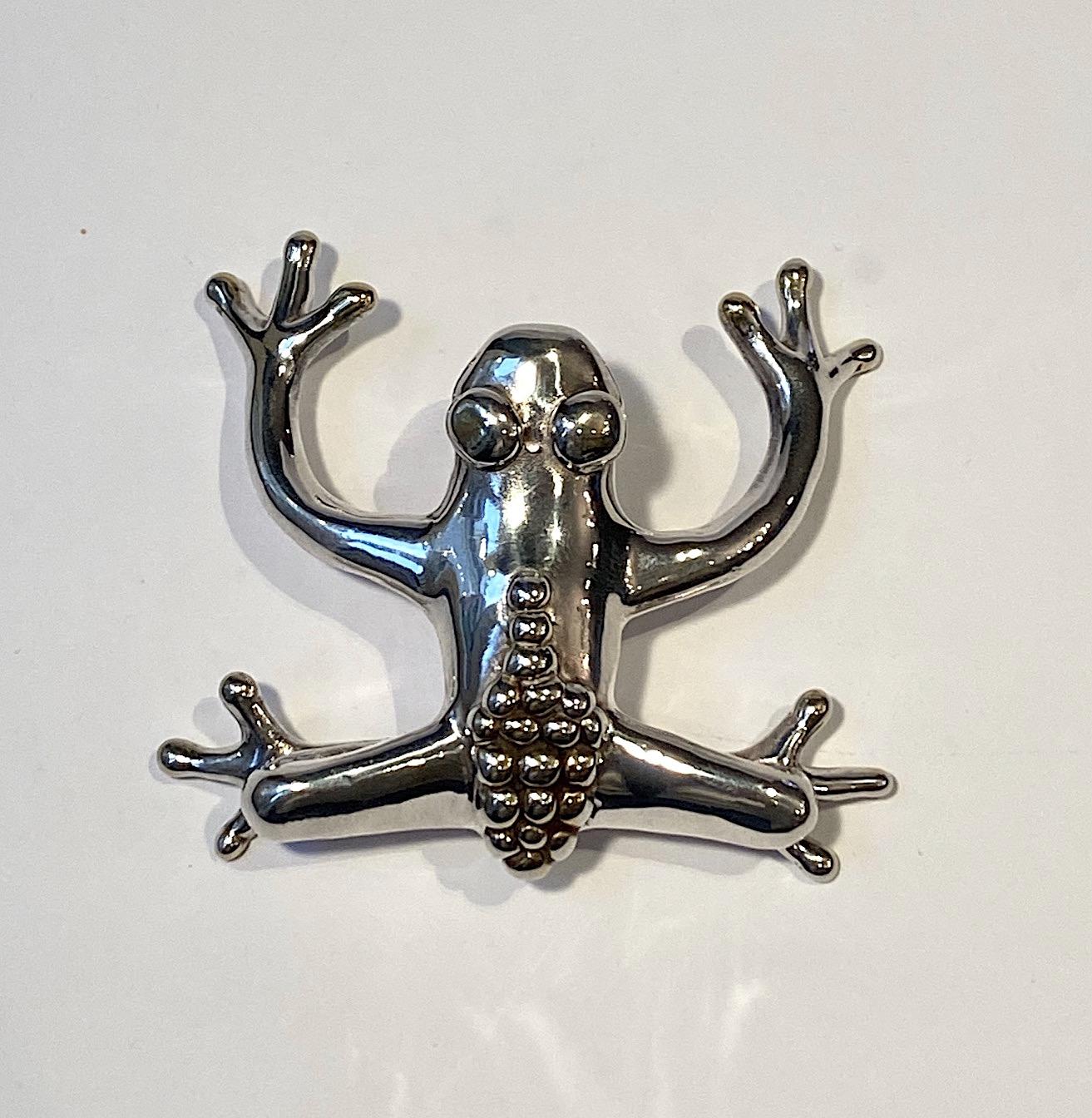 A very large artist made sterling silver frog brooch and pendant from the 1980s. It measures 3.25 inches wide, 3.25 inches long and 1.13inches high. Inscribed on the bottom with artist mark and 925. Ring on the back and behind the head to wear as a