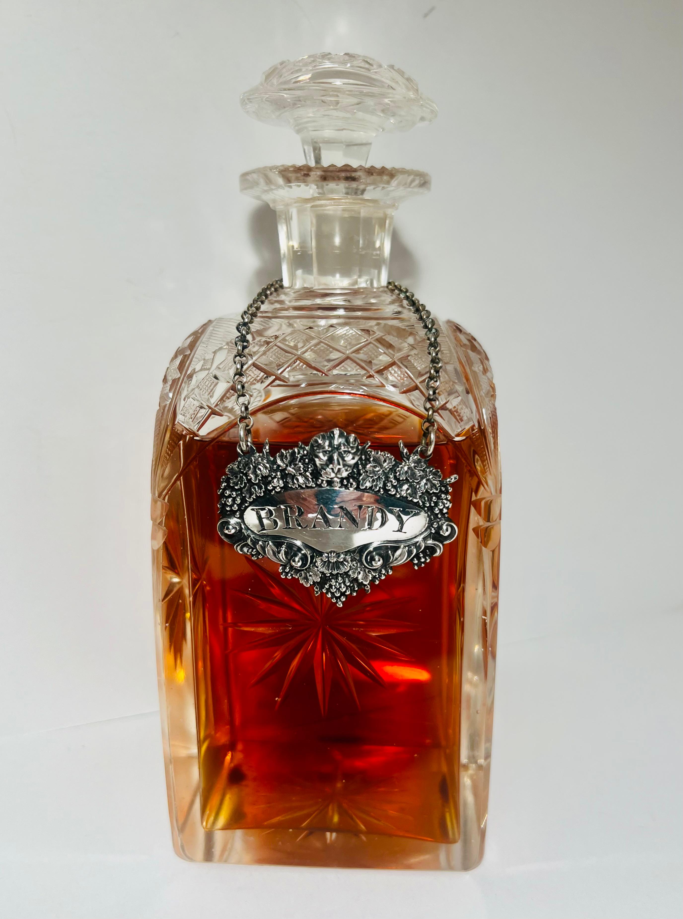 Etiqueta de decantador o ticket de botella, si prefieres el término inglés, para Brandy de Charles Rawlings, Londres, 1828, forjada a mano durante el periodo de Jorge III.  Esta impresionante etiqueta de decantador de plata tiene un relieve profundo