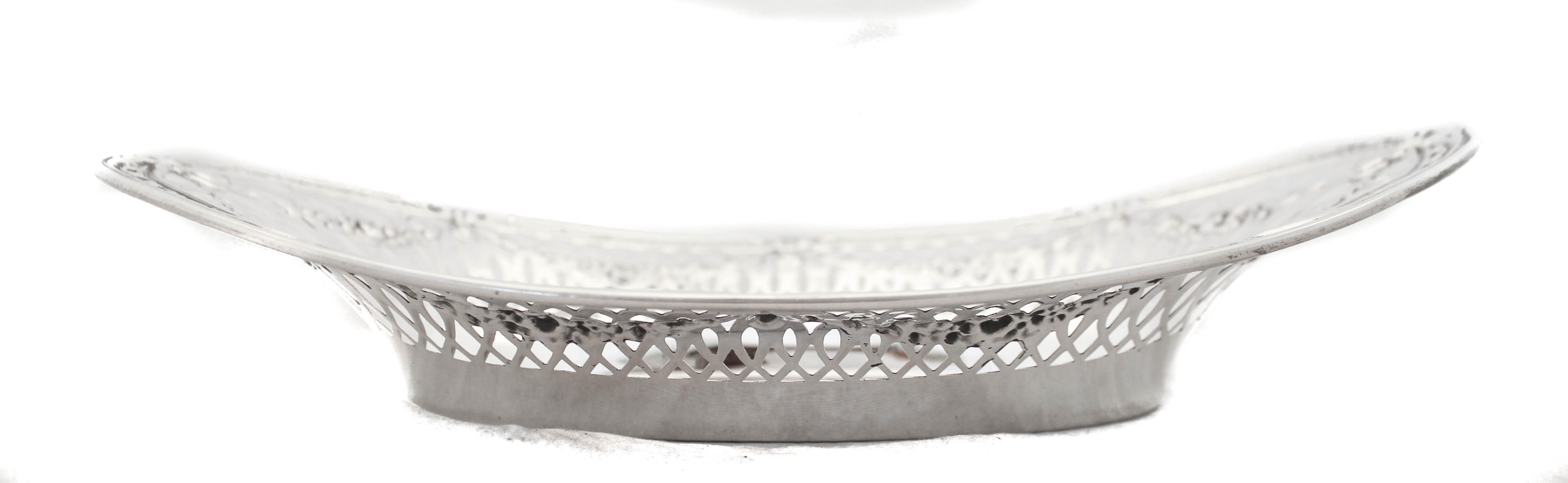 Preciosa panera de plata de ley de la Webster Silver Company; es ornamentada y elegante. Tiene un diseño geométrico recortado alrededor del cuerpo con guirnaldas que lo cubren. A lo largo del borde exterior, un motivo de círculos entrelazados rodea