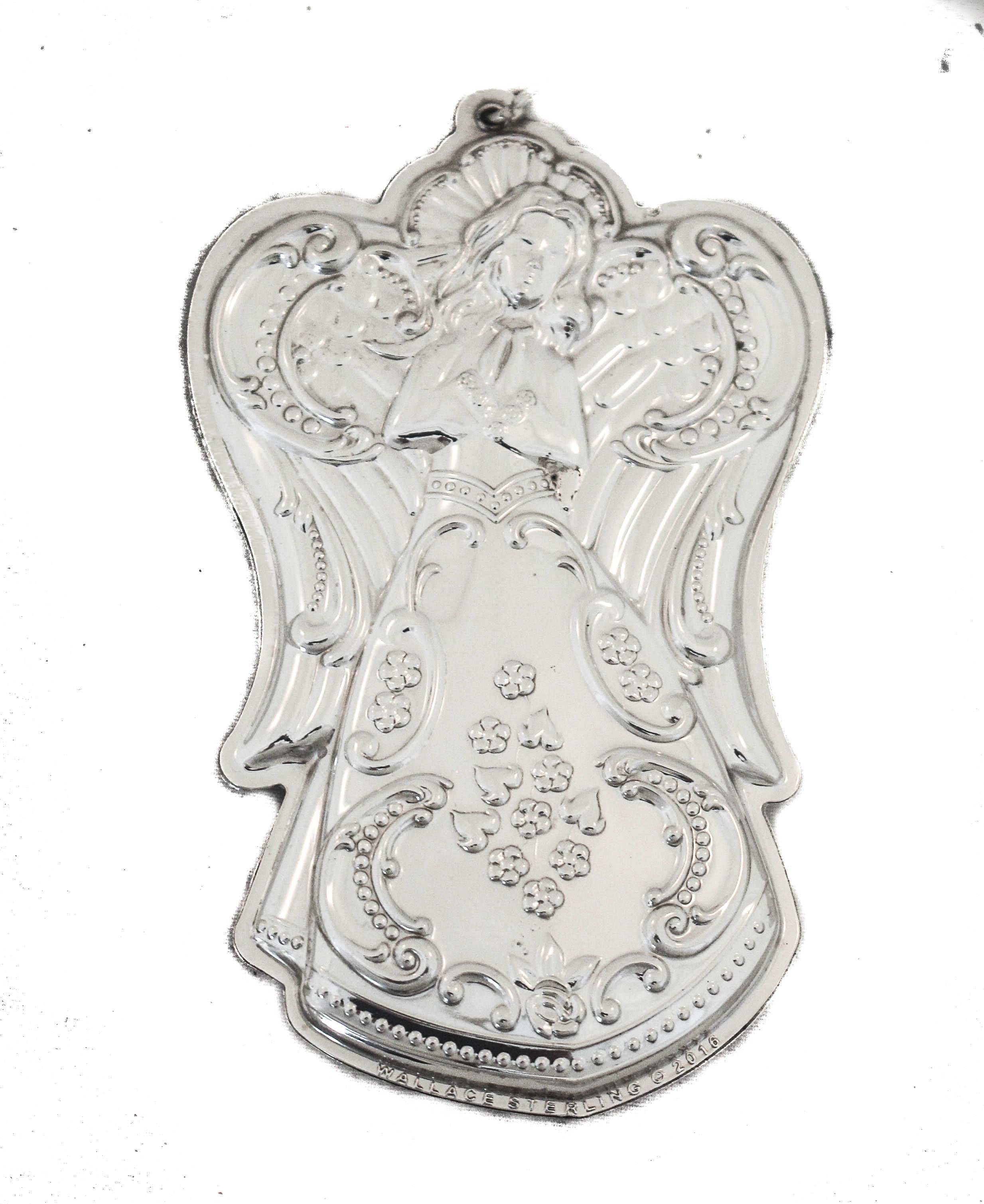 Being offered is a sterling silver Christmas ornament of an Angel by Wallace Silversmiths. 
An Angel with wings, her hands folded in prayer and dressed in a beautiful gown floats in midair. Angels play a huge role in the Christmas story and who