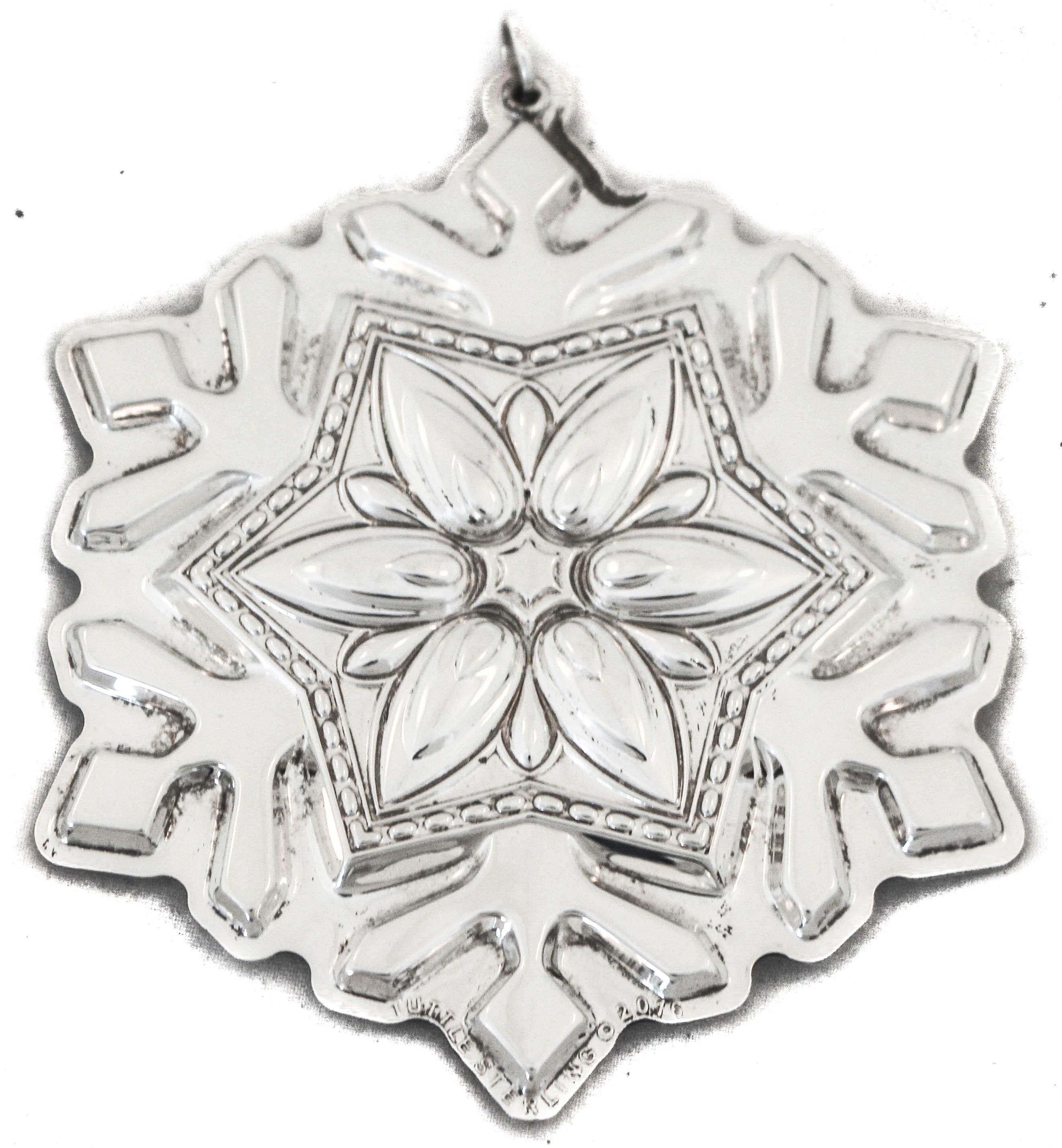 We are happy to offer you this sterling silver Christmas snowflake ornament by the Kirk-Stieff Silver Company of Baltimore, Maryland. 
This snowflake ornament has six points with flowers in the dip of each and a large flower in the center. Both