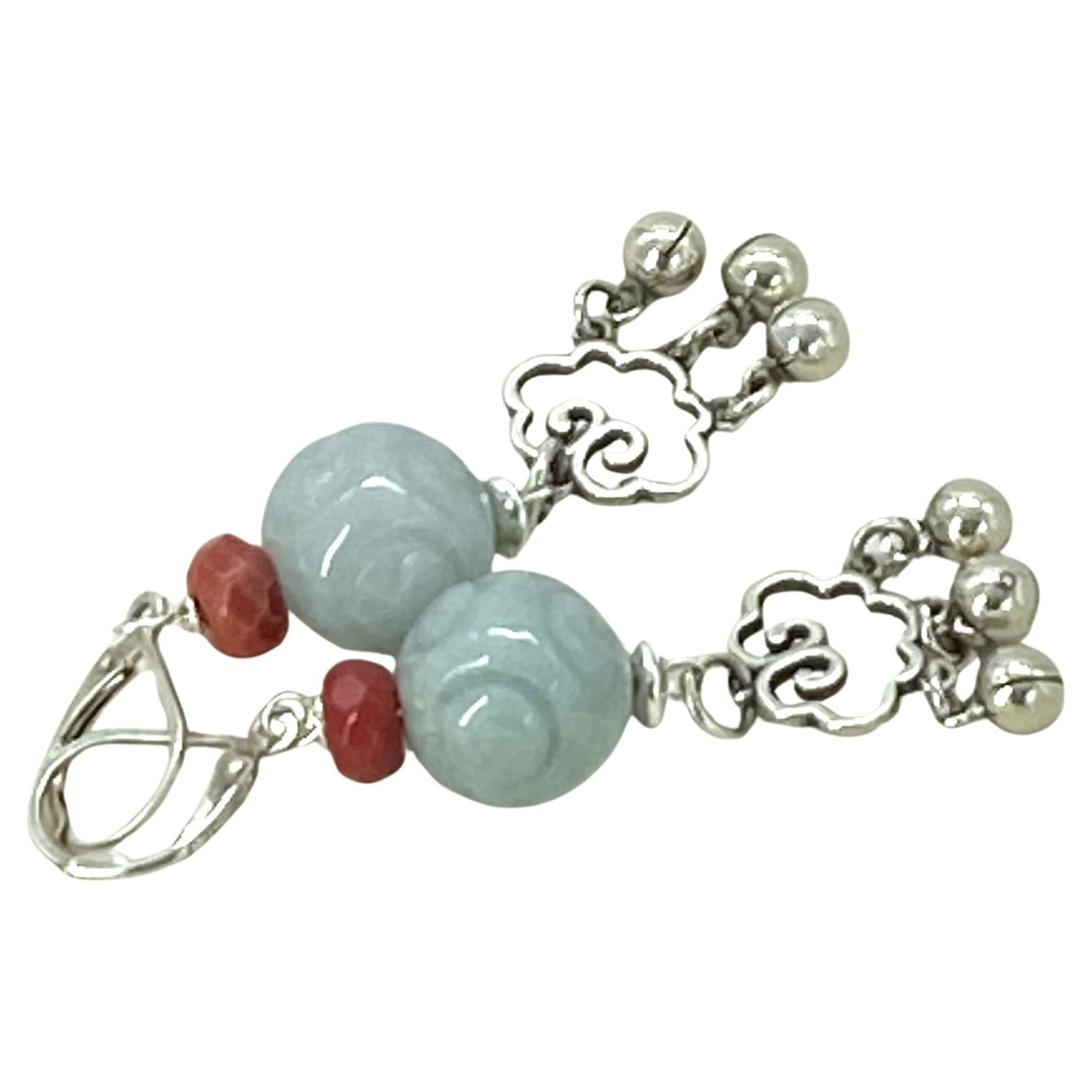 Si tratta di un paio di divertenti orecchini pendenti in giadeite e corallo. Li abbiamo creati con giadeite di grado A intagliata da 13,5 mm, corallo naturale sfaccettato e charms a forma di nuvola in argento sterling con gocce a forma di campana.