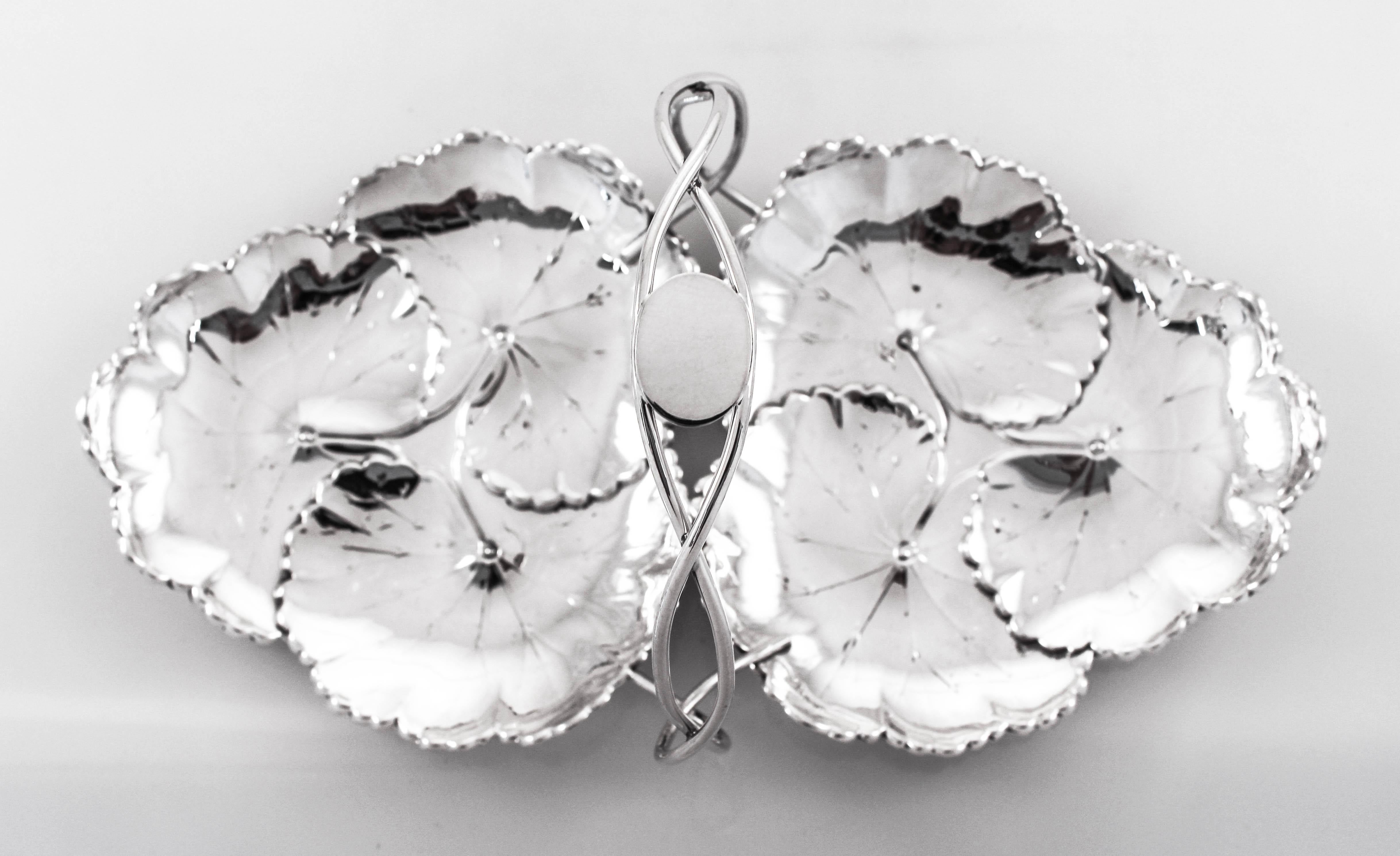 This sterling silver dish has a handle in the centre and connects two seemingly separate dishes together. Designed and manufactured at the height of the Art Nouveau movement in the early 20th century, each dish is shaped and designed to look like
