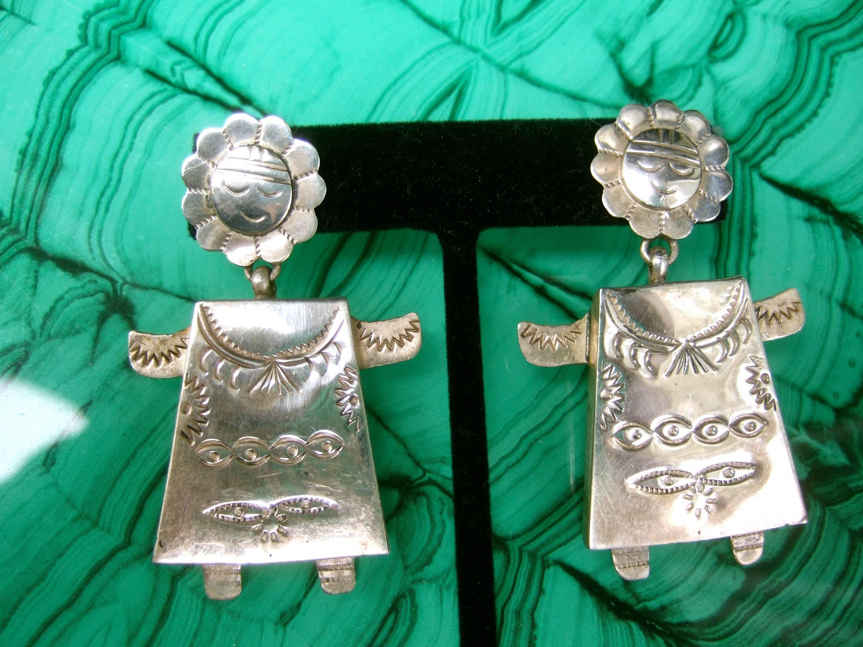 Sterling figural Mexican artisan dangle earrings c 1980s
The unique handmade figural pierced earrings 
are designed with smiling etched faces 
with a wreath of flower pedals that circles
the head

The chunky hinged dangling bodies have 
impressed