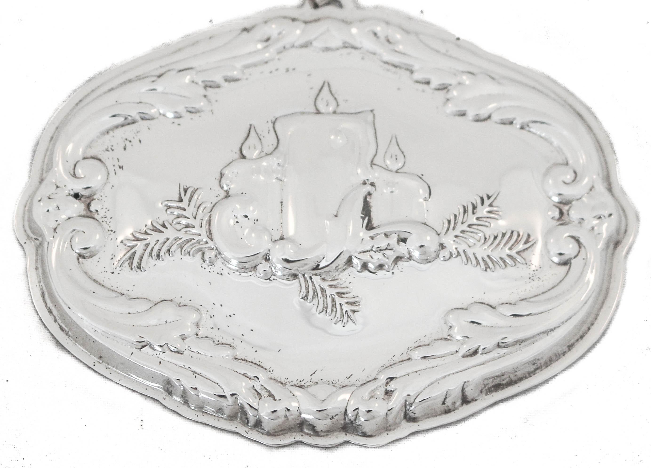 We are happy to offer you this sterling silver Christmas ornament in the Francis I pattern by Reed and Barton. The rim is scalloped with an ornate border. On one side three candles burn with Yule branches surrounding them. On the other side, it’s