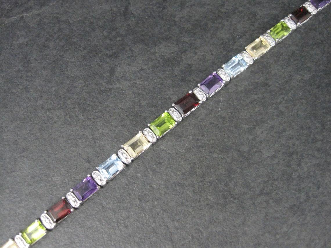 This gorgeous estate bracelet is sterling silver.
It features 5x7mm garnets, citrines, peridot, amethysts and topaz and is the product of Ross Simons.

Measurements: 1/4 of an inch wide, 7 1/2 wearable inches

Condition: Phenomenal
