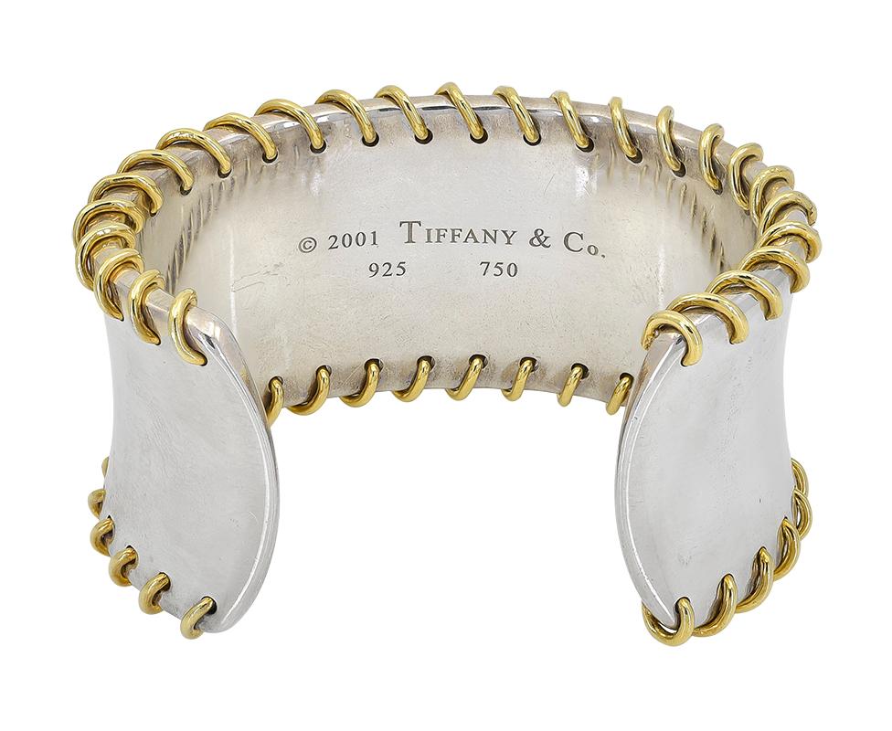 Striking sterling silver cuff bracelet with 18K yellow gold stitch pattern around both borders.  Made and signed by TIFFANY & CO.  1 1/2