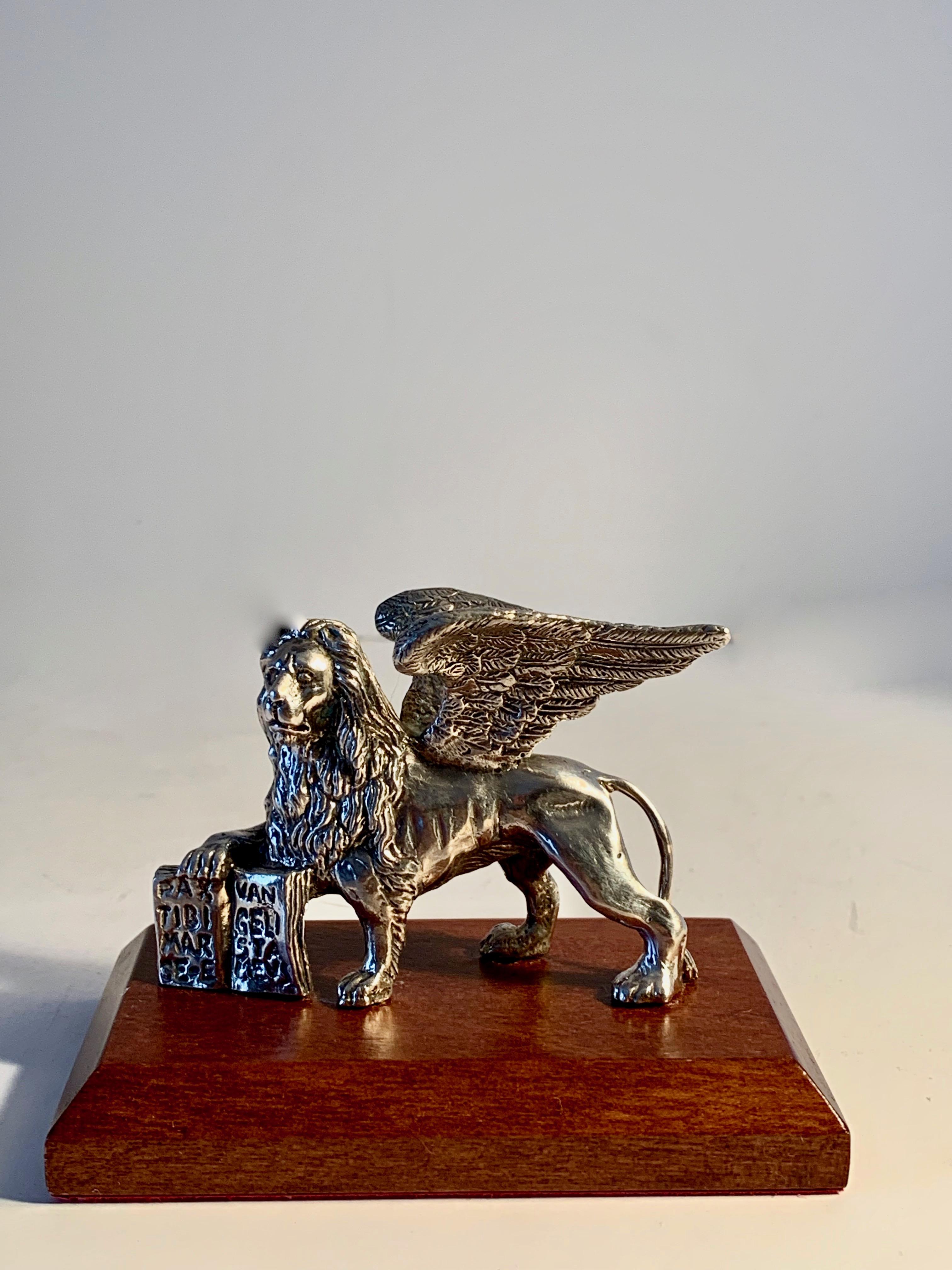 A Winged Lion of St Mark on wooden base, the lion has been tested and is solid sliver, standing on a wooden base the piece is a handsome bookmark, or decorative desk sculpture. A lovely and understated piece for any room

The Lion of Saint Mark,