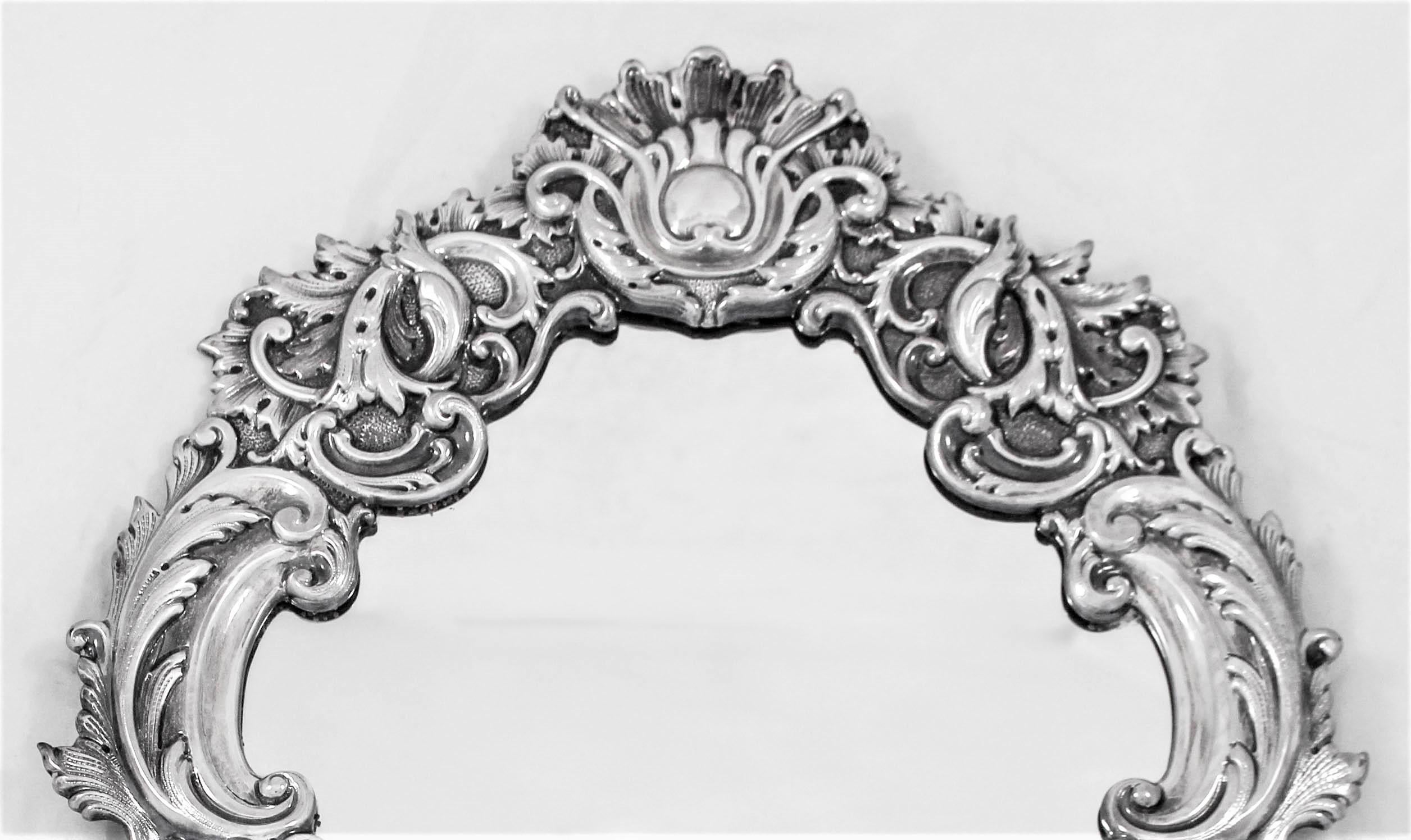 We are delighted to offer this sterling silver vanity mirror, designed in the Rocco style. Being French, it is very grandiose and has a Versailles opulence to it. It has layers of swirls overlapping each other with both the outer and inner rims