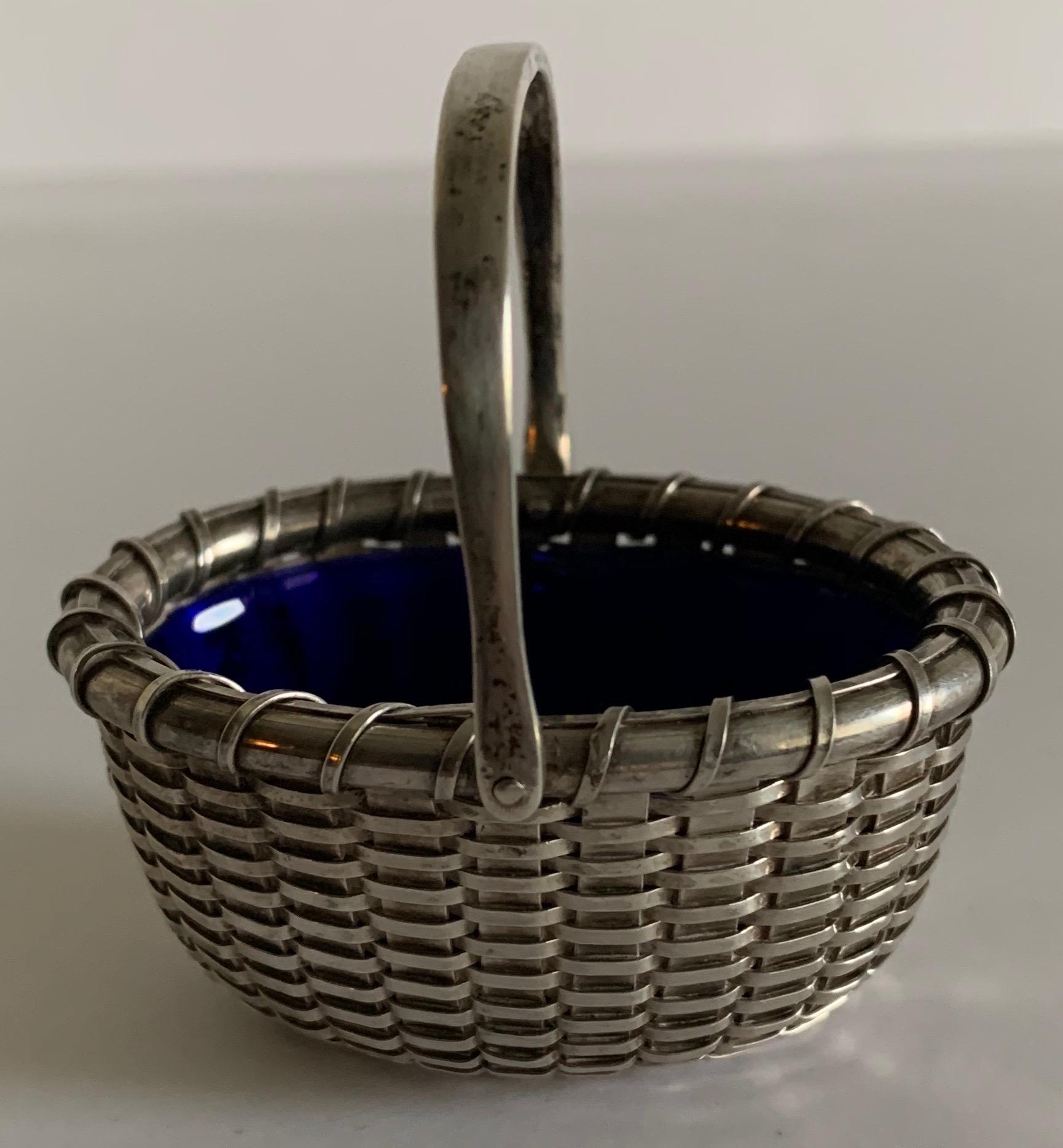 Sterling silver Nantucket basket salt cellar by Bethany Borzilleri. Miniature oval sterling woven basket with attached handle. Cobalt glass liner. Signed “Bethany Borzilleri 1999”on the underside.
