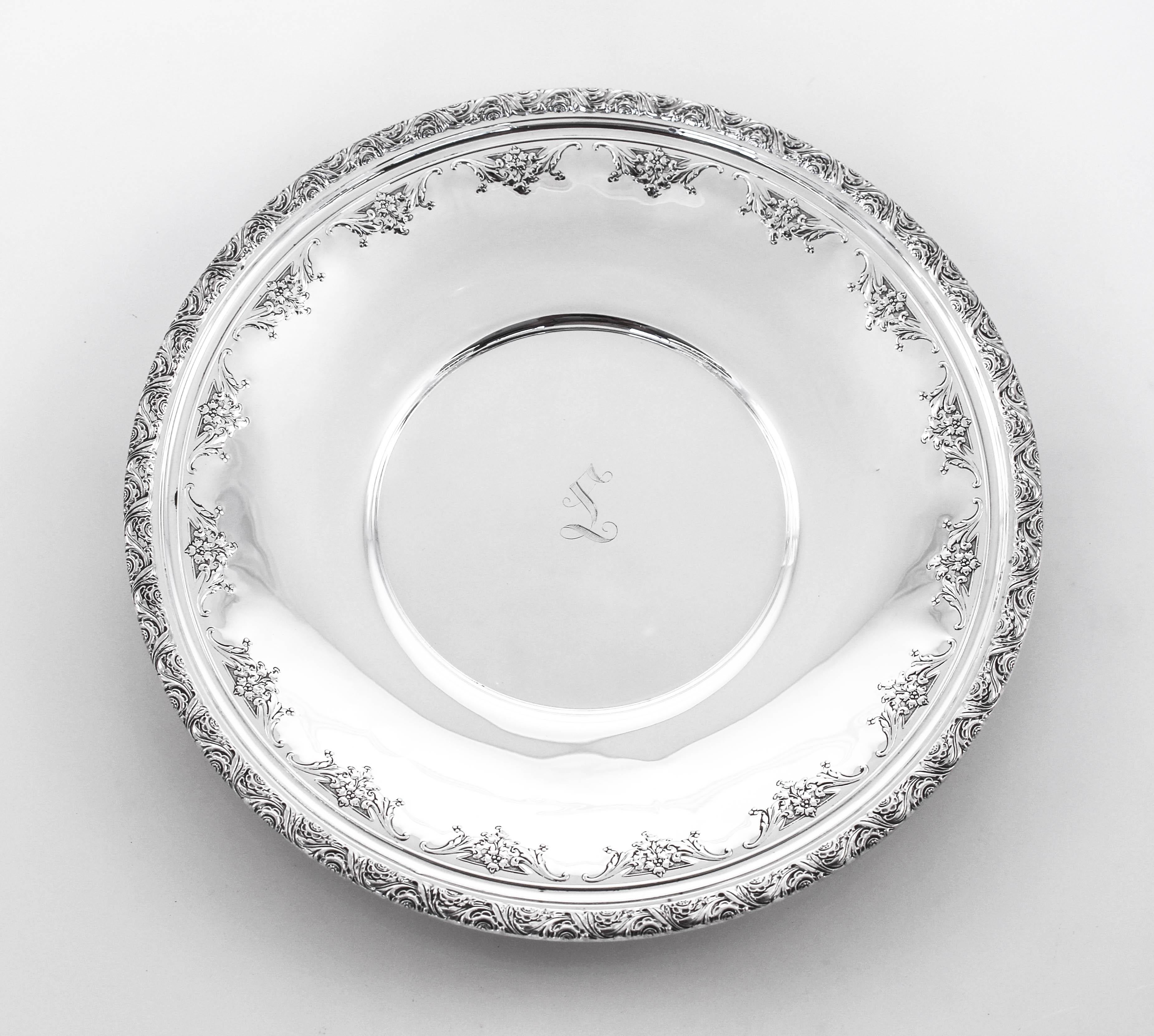 This sterling silver dish is so feminine and bridal-like. Clusters of flowers circle the entire inner rim. Along the outside perimeter a decorative motif can be found. In the center there is a script hand engraved L. A nice size for snacks or
