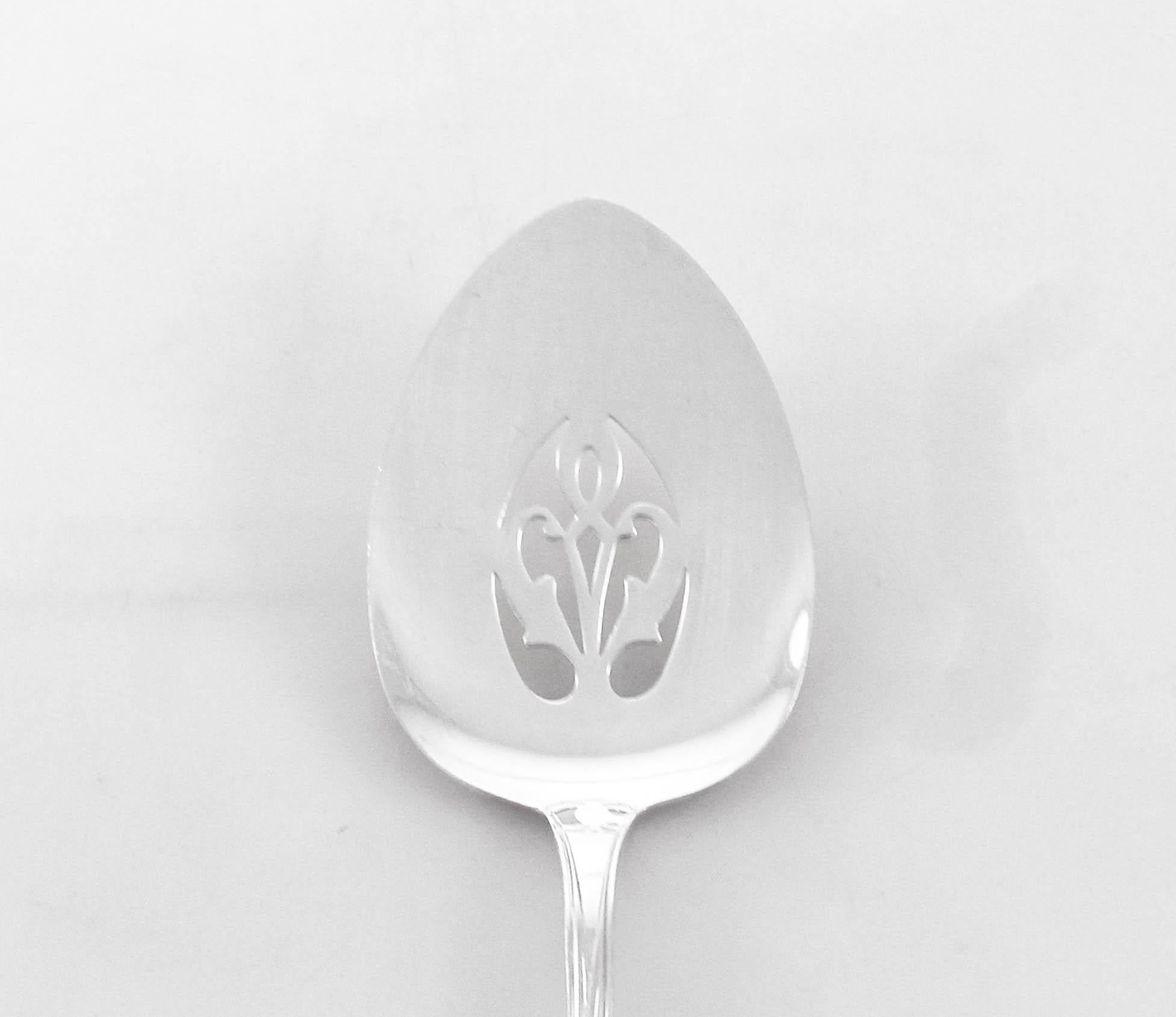 A sterling silver server by Lunt Silversmiths in the Quintessence pattern. The handle has raised flowers and branches and there is pierced work on the top portion. Ideal for serving quiche, vegetables or anything baked.