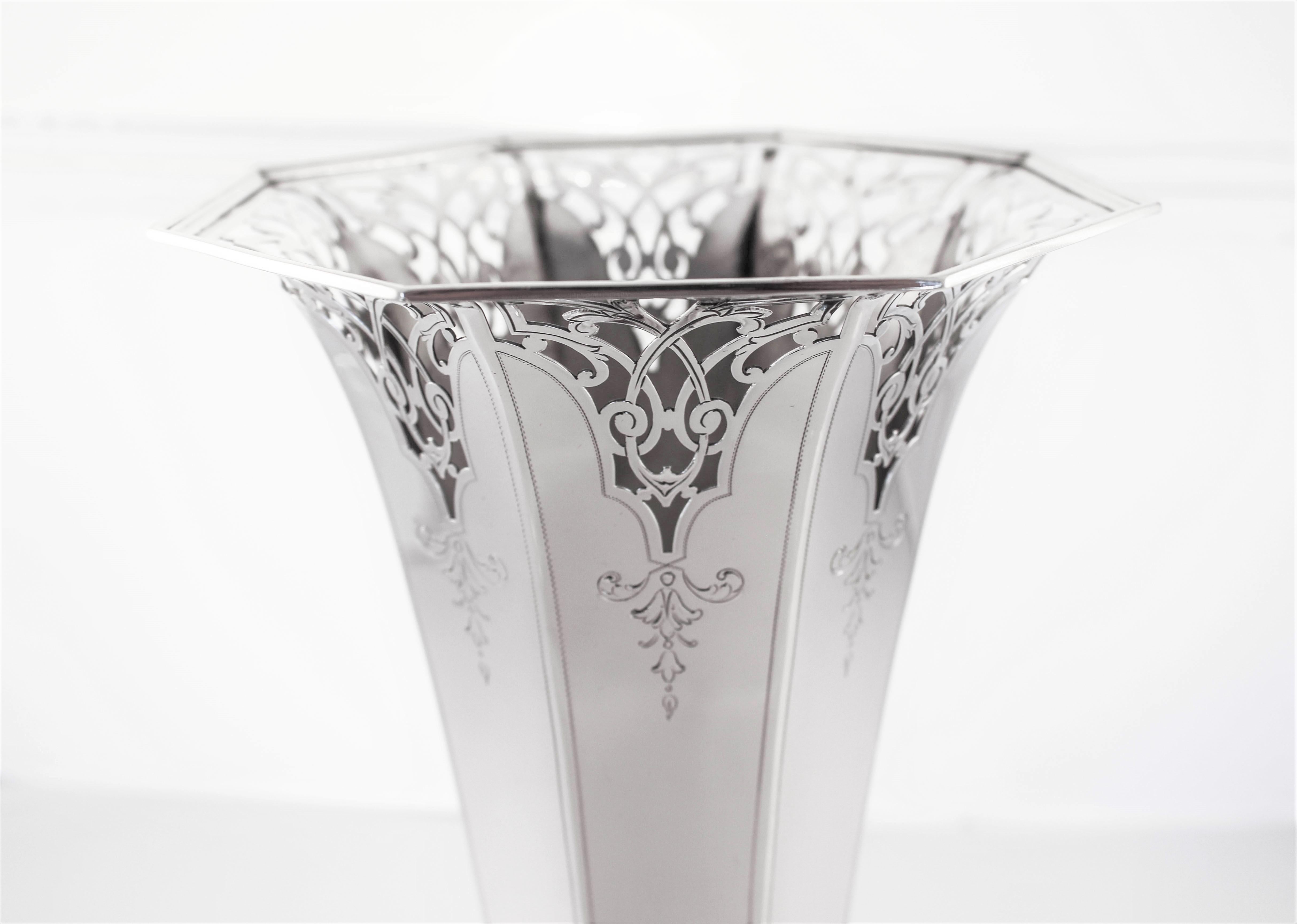 We are thrilled to present this antique sterling silver vase from the late 1890s. It is a throwback to the gilded age when detail and precision were valued. It has an octangular shape and matching base. Along the top a reticulated pattern gives it