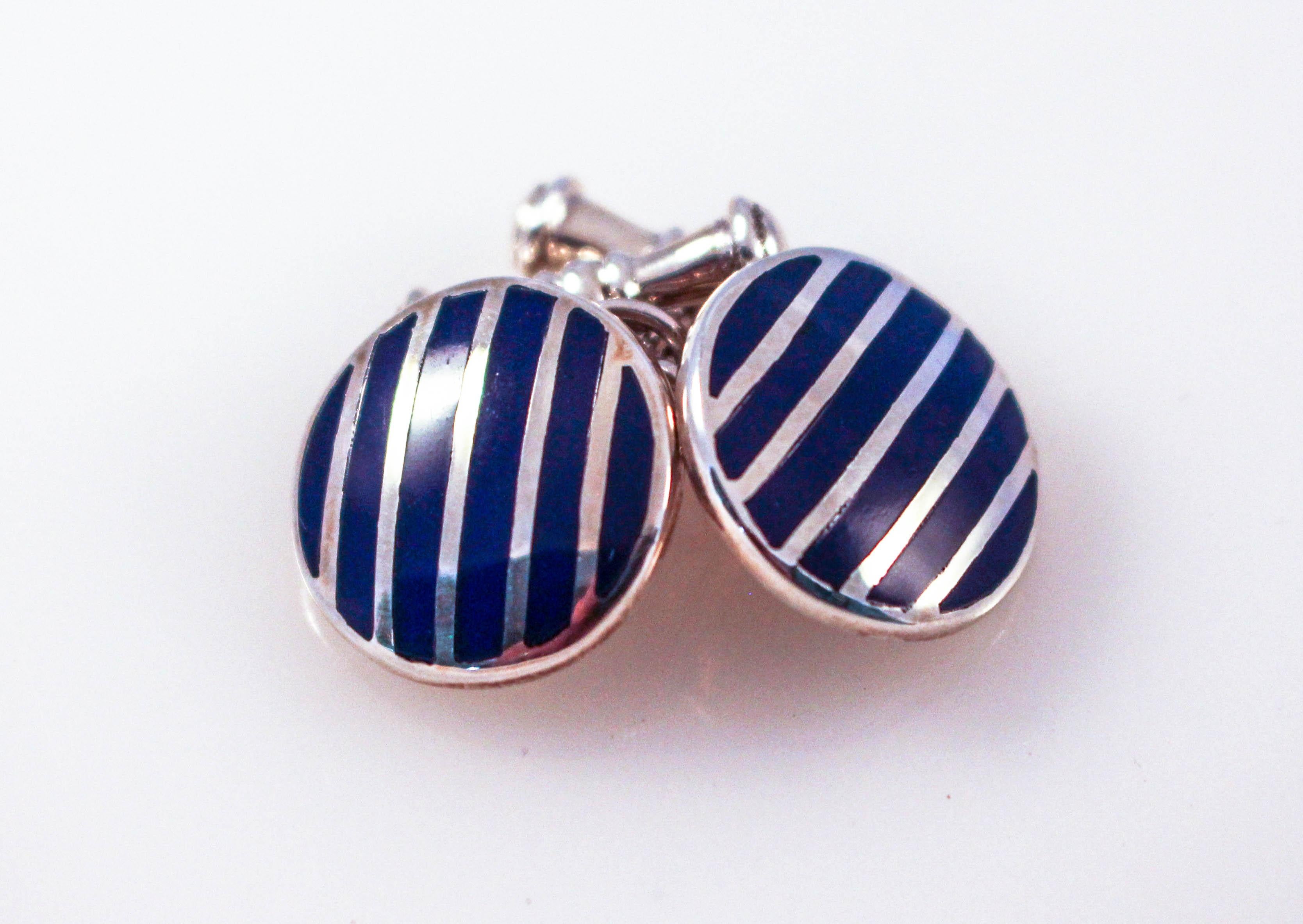 Just in time for Father’s Day and/or graduation, we are offering these sterling silver cufflinks. Made in England, they are blue with a silver stripes across the front. They pop-out and give color and style to an otherwise serious look. They can be