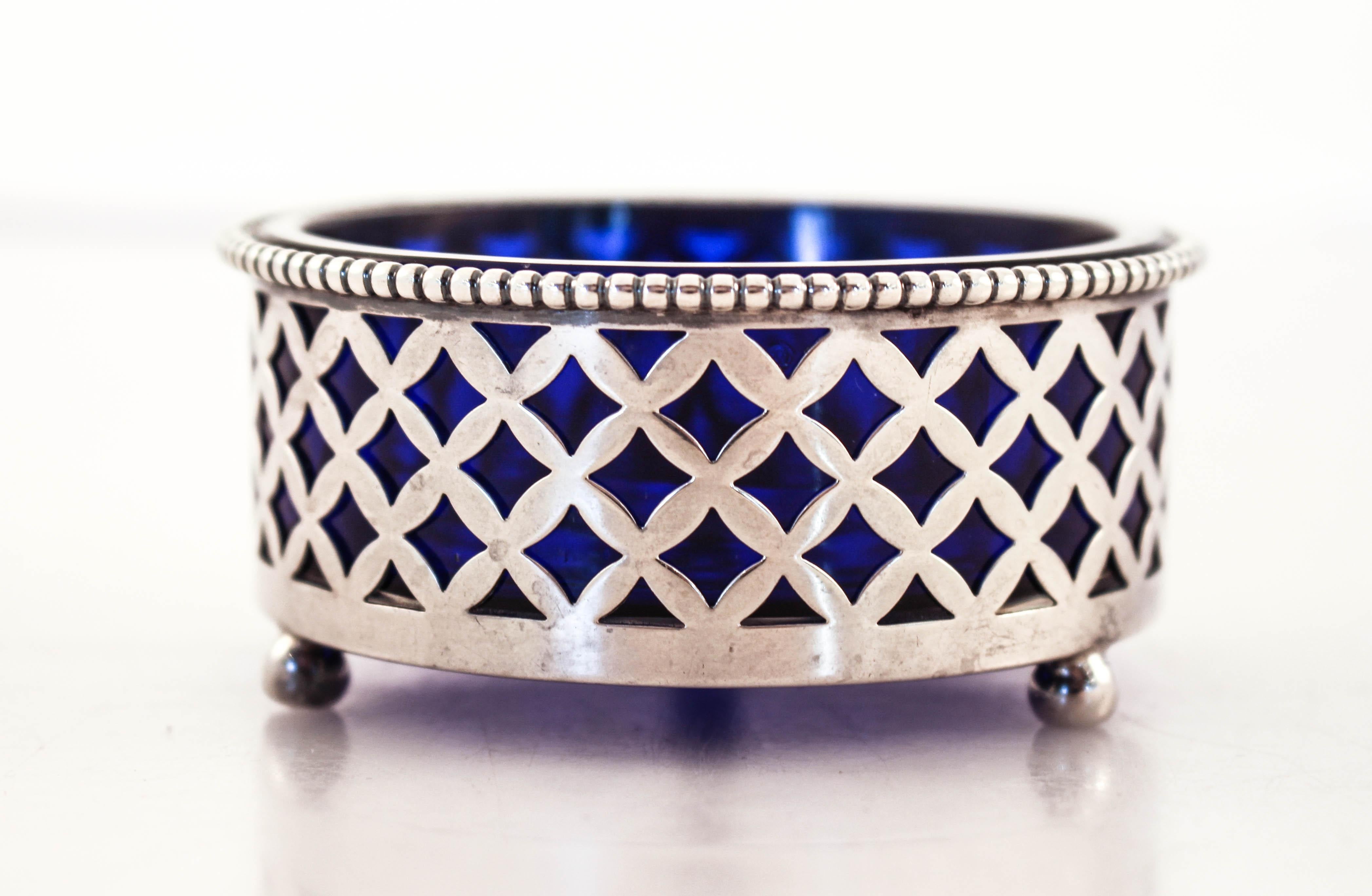 A sterling silver salt cellar with a cobalt blue liner. Standing on three balls, it has a latticework pattern. Through the silver, the deep blue of the cobalt pops out. The glass liner comes out so it’s easy to clean and refill. The perfect touch to
