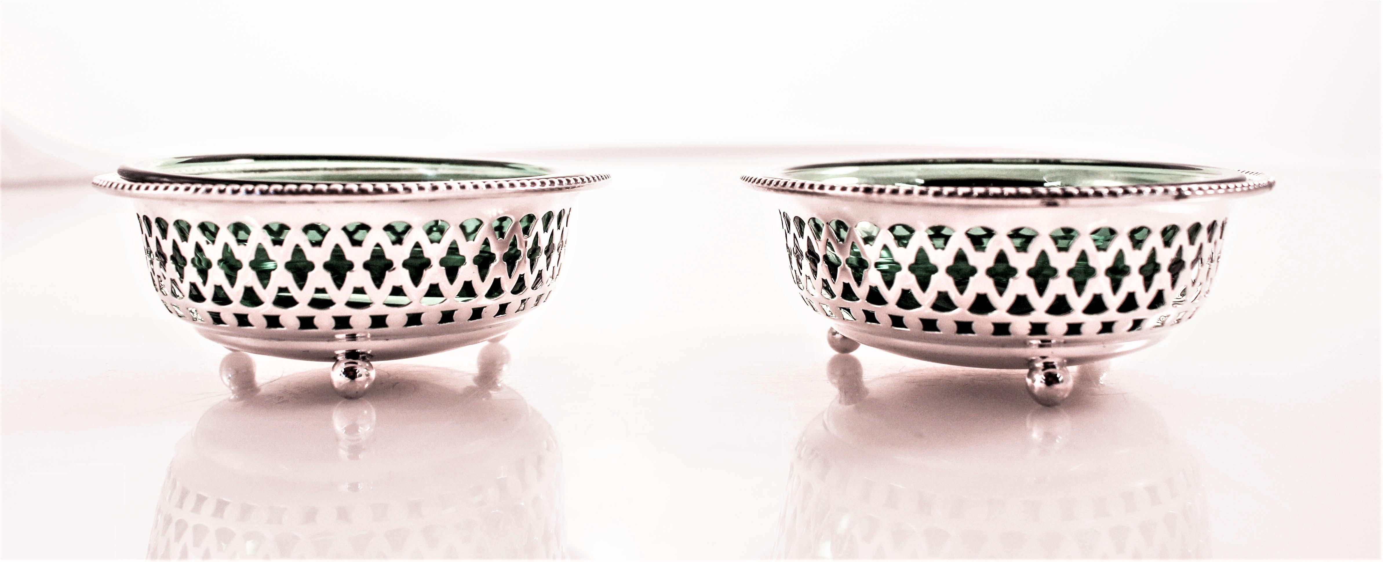 A pair of sterling salt cellars by the Gorham Corporation of Rhode Island. The have lattice work around the entire body and removable green liners to hold the salt. The rich green glass looks stunning and pops out from between the cutout work. They