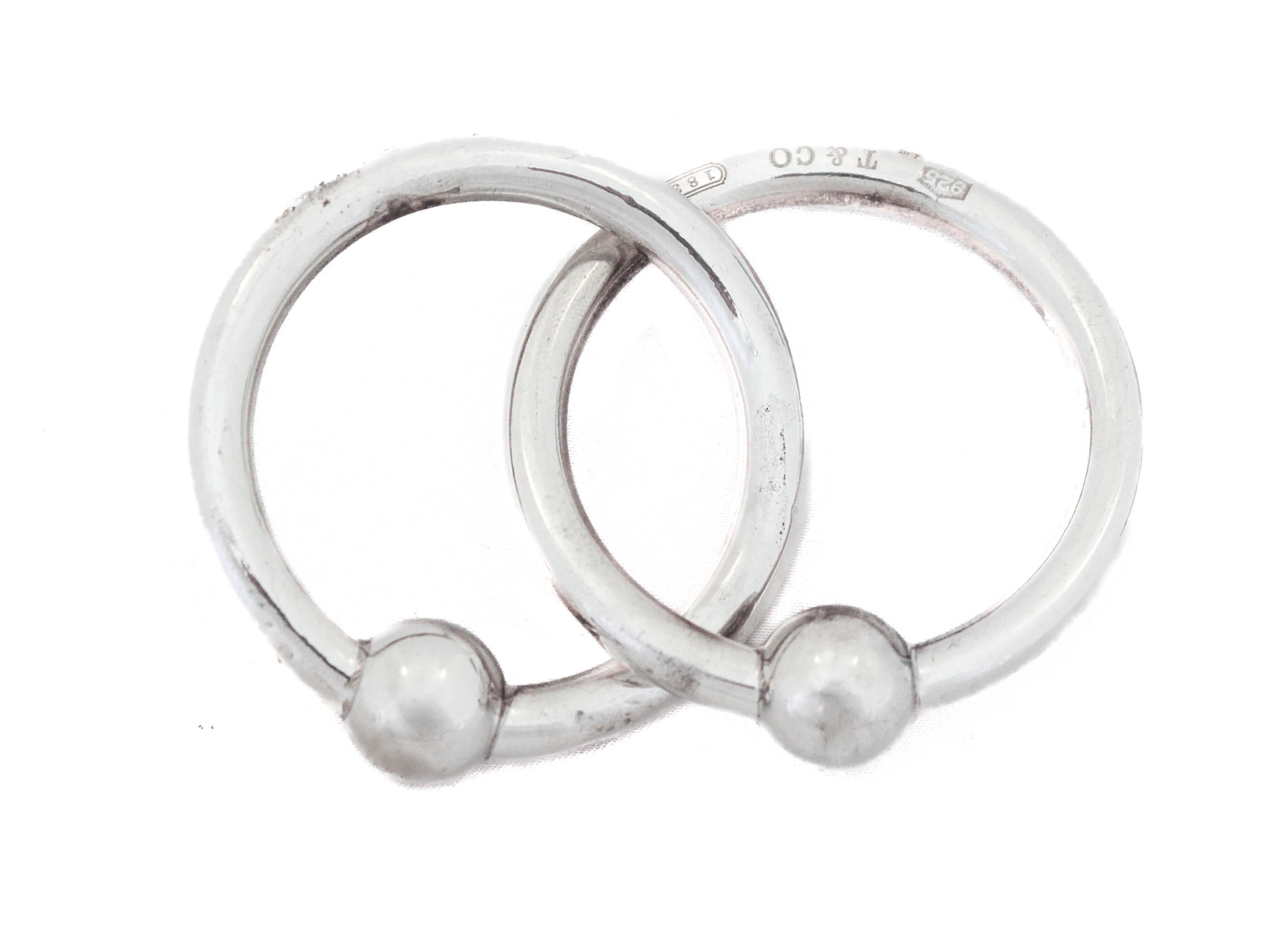Nous proposons des anneaux de hochet en argent sterling de la marque de renommée mondiale Tiffany and Company.  Deux anneaux d'argent s'entrecroisent pour les maintenir ensemble.  L'élégance et la sophistication du milieu du siècle pour un bébé du