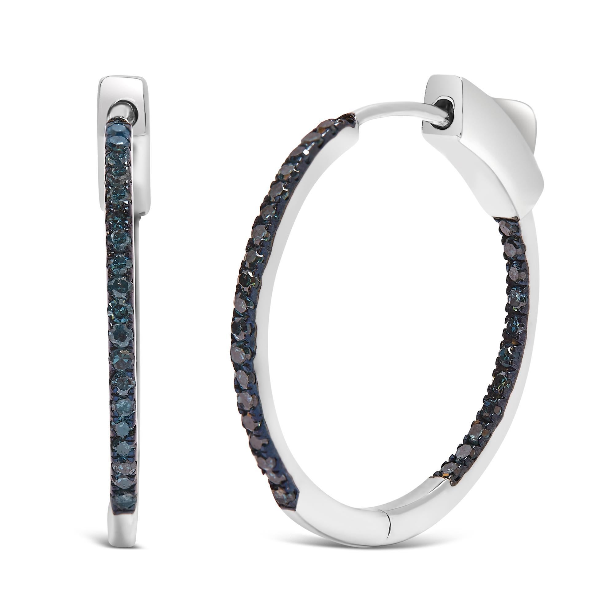 Realizzati in argento 925 rodiato, questi squisiti orecchini a cerchio offrono una silhouette sottile e aggraziata, con una larghezza di 1 mm e un delicato pendente di 3,5 cm. Adornate da una vibrante serie di diamanti blu trattati, per un totale di