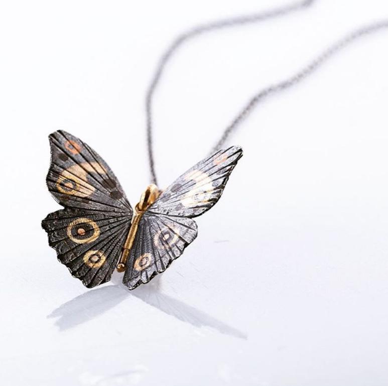 James Banks's signature butterfly necklace features a Buckeye butterfly with a hinge at the center to allow movement of the wings, set in oxidized Sterling Silver with 18k Yellow Gold, 14k Rose Gold, Rose Bronze, and Copper Inlay hung on an oxidized