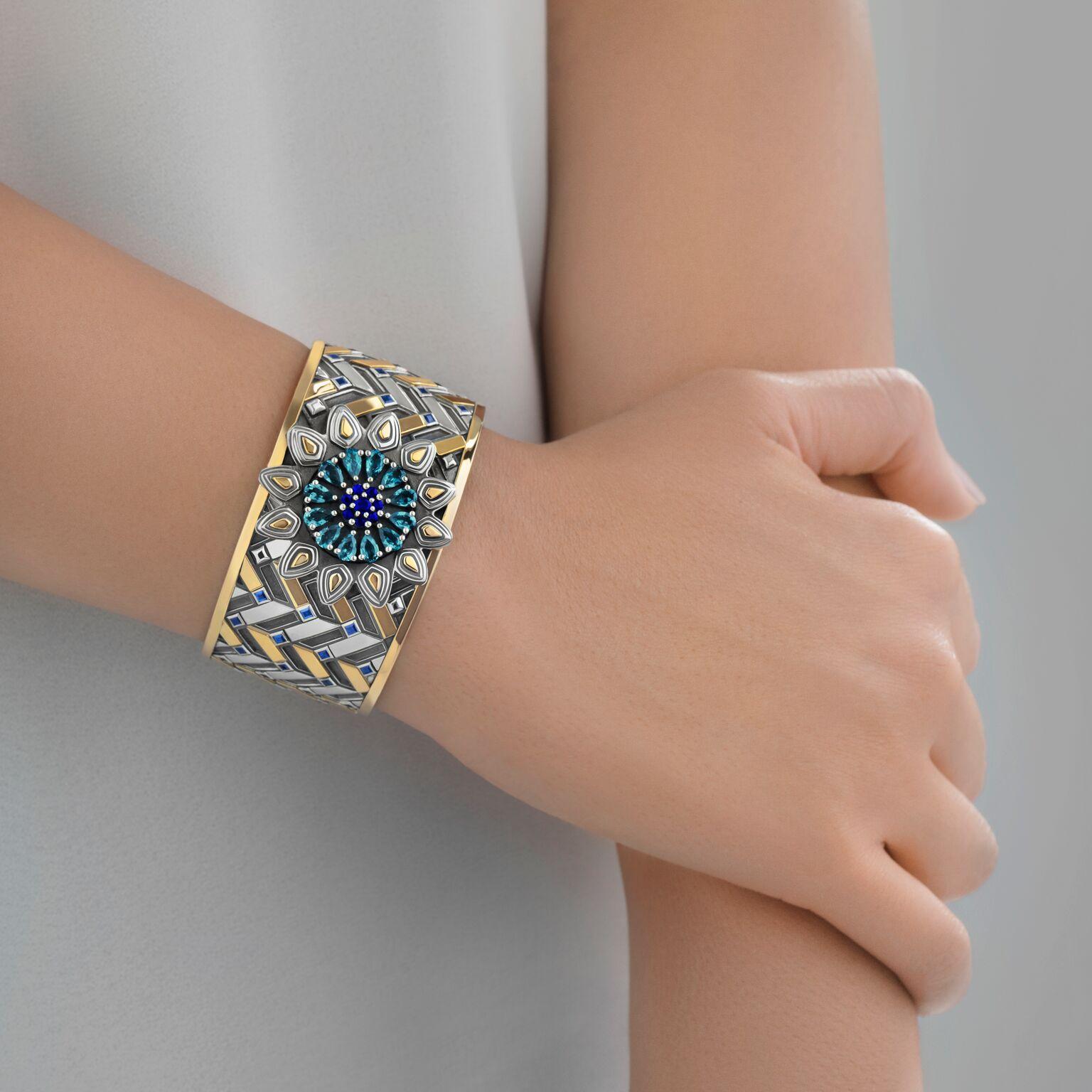 Sterling Silver, 18 Karat Yellow Gold, 2.33 carat Sapphire and 4.50ct London Blue Topaz Qalawun-Muzhir Bangle inspired by the Mamluk period in Medieval Egyptian History.

The Qalawun-Muzhir Bangle brings together two design compositions: the first