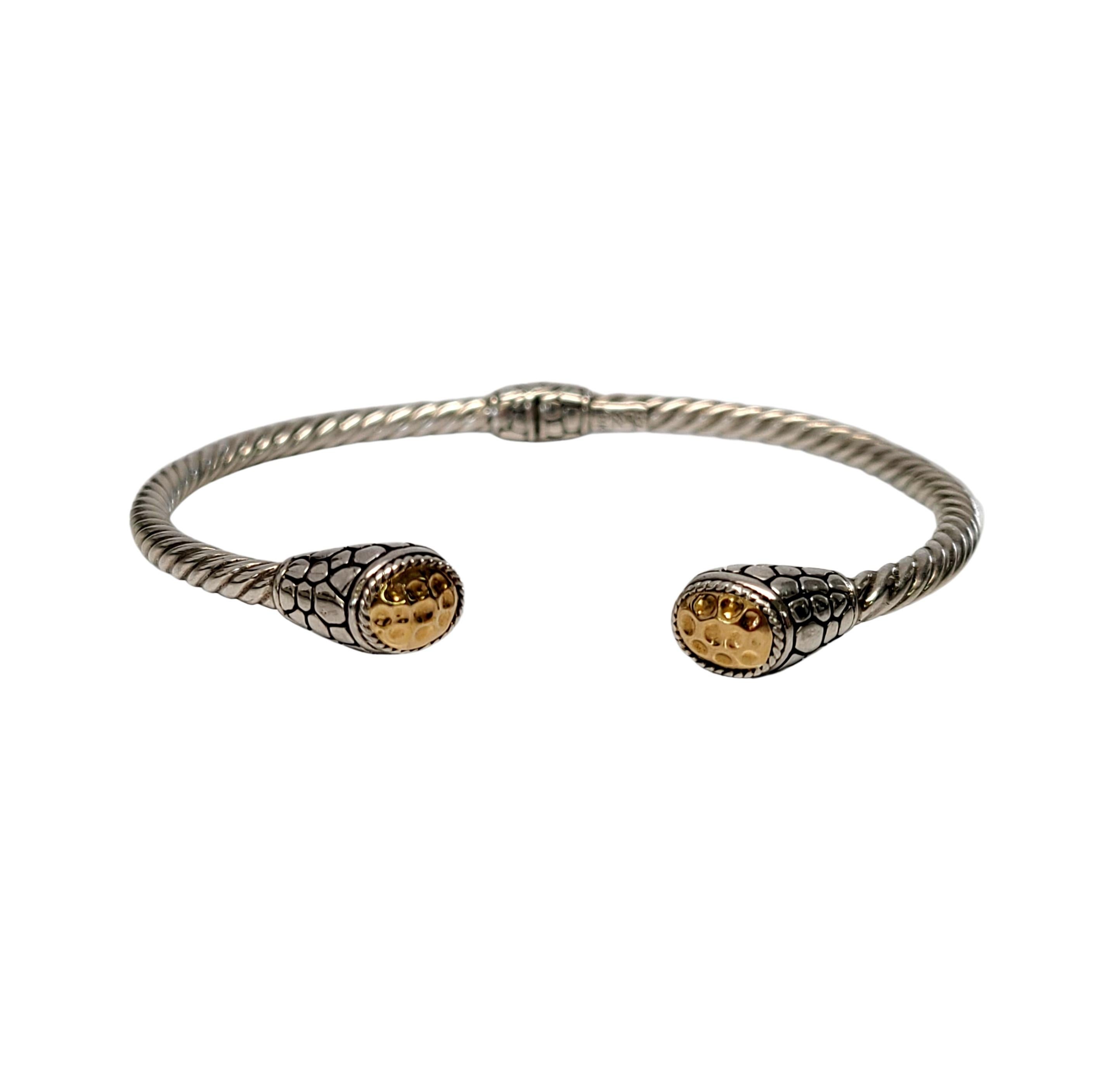Sterling silver and 18K gold accent hinged cuff bracelet.

Designer artisan piece featuring a hinged twisted cable cuff with pebble design ends and 18K yellow gold hammered accent end caps.

Measures approx 6 1/2