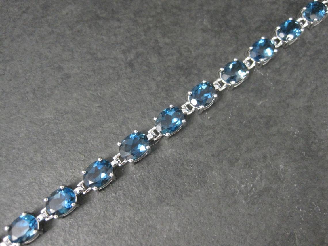 This gorgeous estate bracelet is sterling silver.
It features 17 oval 6x8mm, 1.3 carat blue topaz gemstones.

Measurements: 1/4 of an inch wide, 7 1/2 wearable inches
Weight: 19.1 grams

Marks: R8T, 925, Thailand