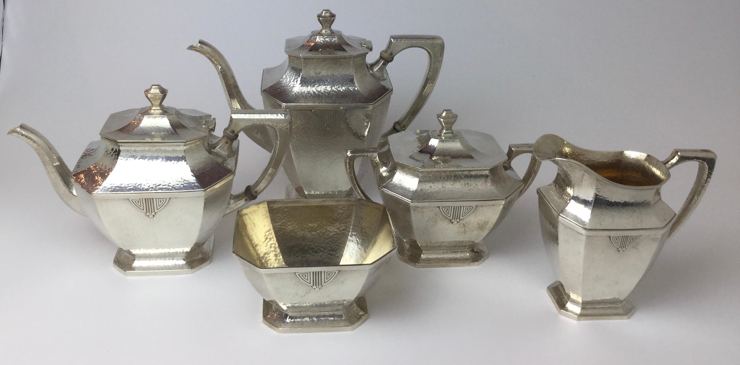 An exceptional early 20th century solid sterling silver tea service with lightly hand hammered surface. The set is from circa 1905 complete with a coffee pot, tea pot, covered sugar, creamer and waste bowl. All pieces with 8 sides with a small
