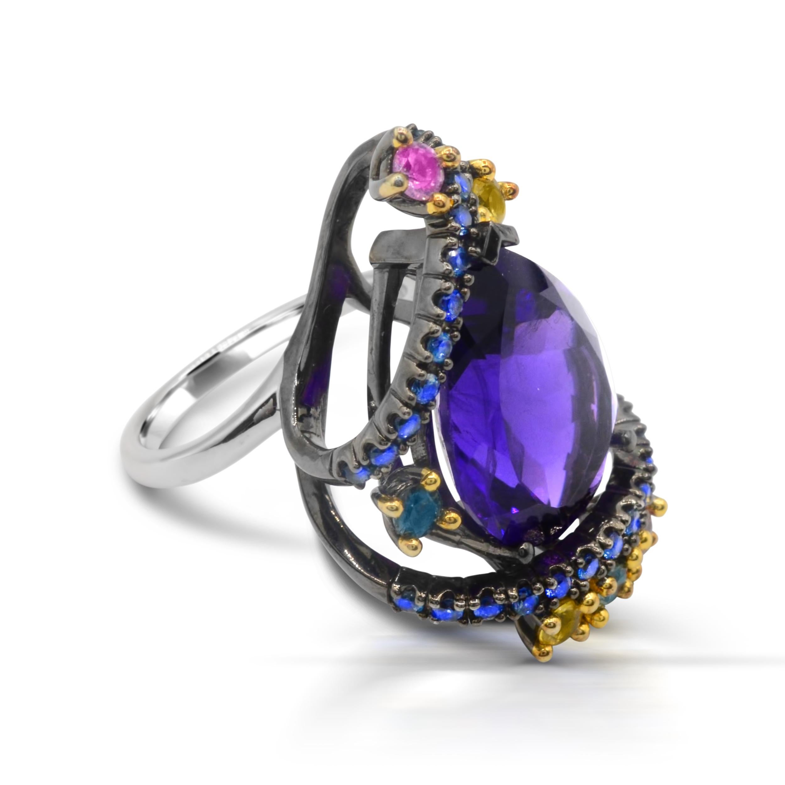 An exquisite ring that features 18x13 Pear-shaped Amethyst accented with Multicolor Natural Sapphire around it.  Crafted in Sterling silver with a beautifully constructed undergallery and black rhodium embraced detailing, this ring shines with a