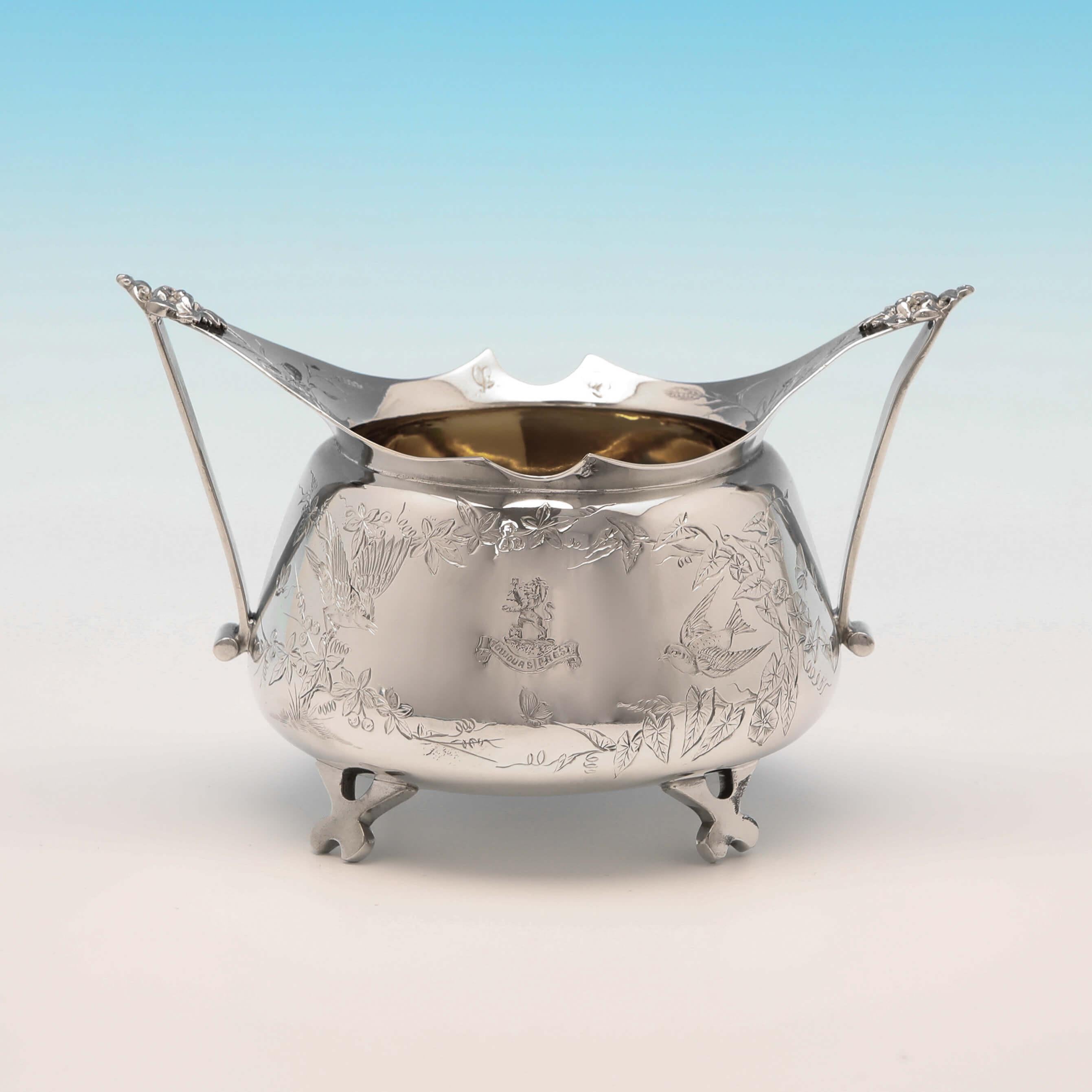Hallmarked in London in 1881 by Stephen Smith, this striking, Victorian, antique sterling silver sugar and cream set, is in the Aesthetic Movement style, featuring wonderfully engraved decoration, an engraved crest and motto to each, gilt interiors