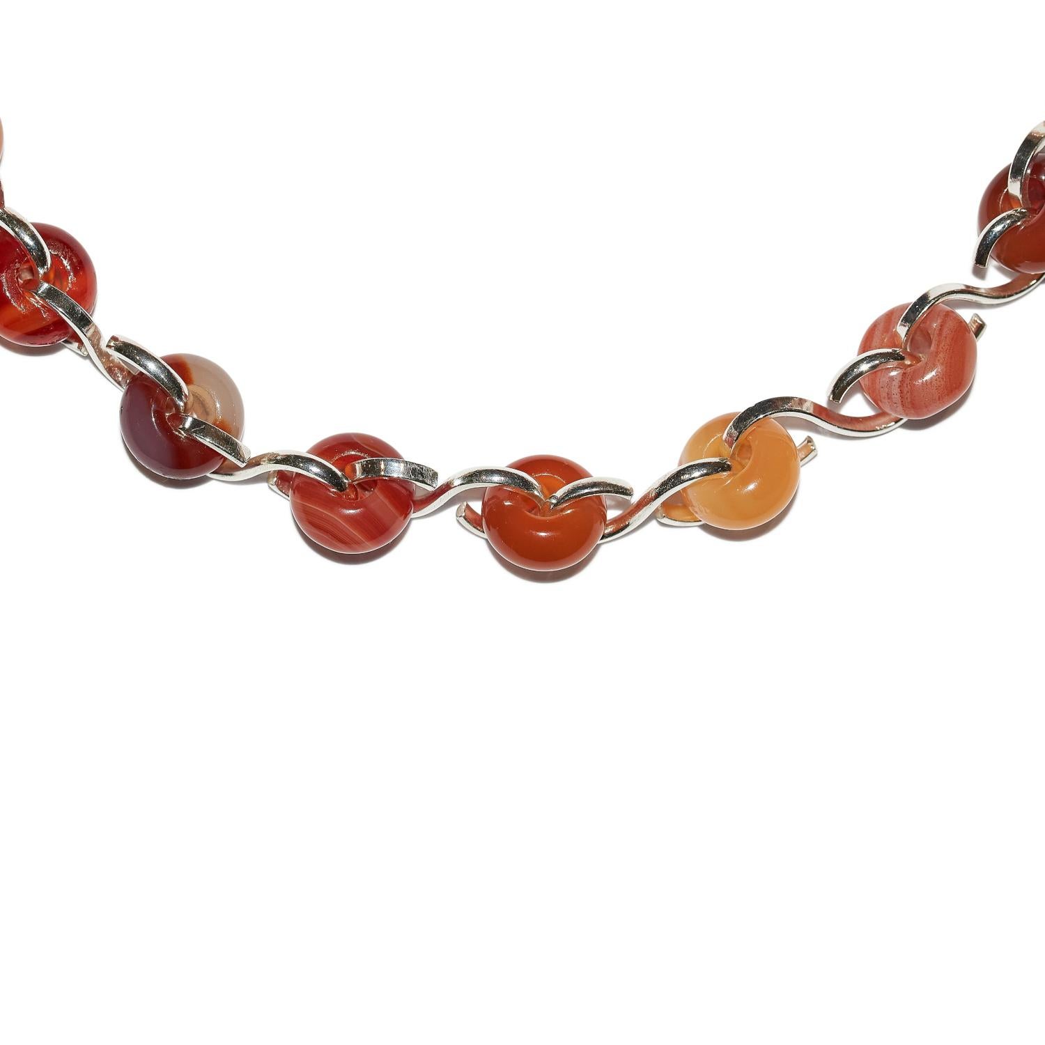 The Ornate Poise Collar necklace in sterling silver with chunky agate rondelle beads is carefully handcrafted in our North London studio. Each sterling silver link is handmade to hold the agate beads in place whilst creating a continuous loop around
