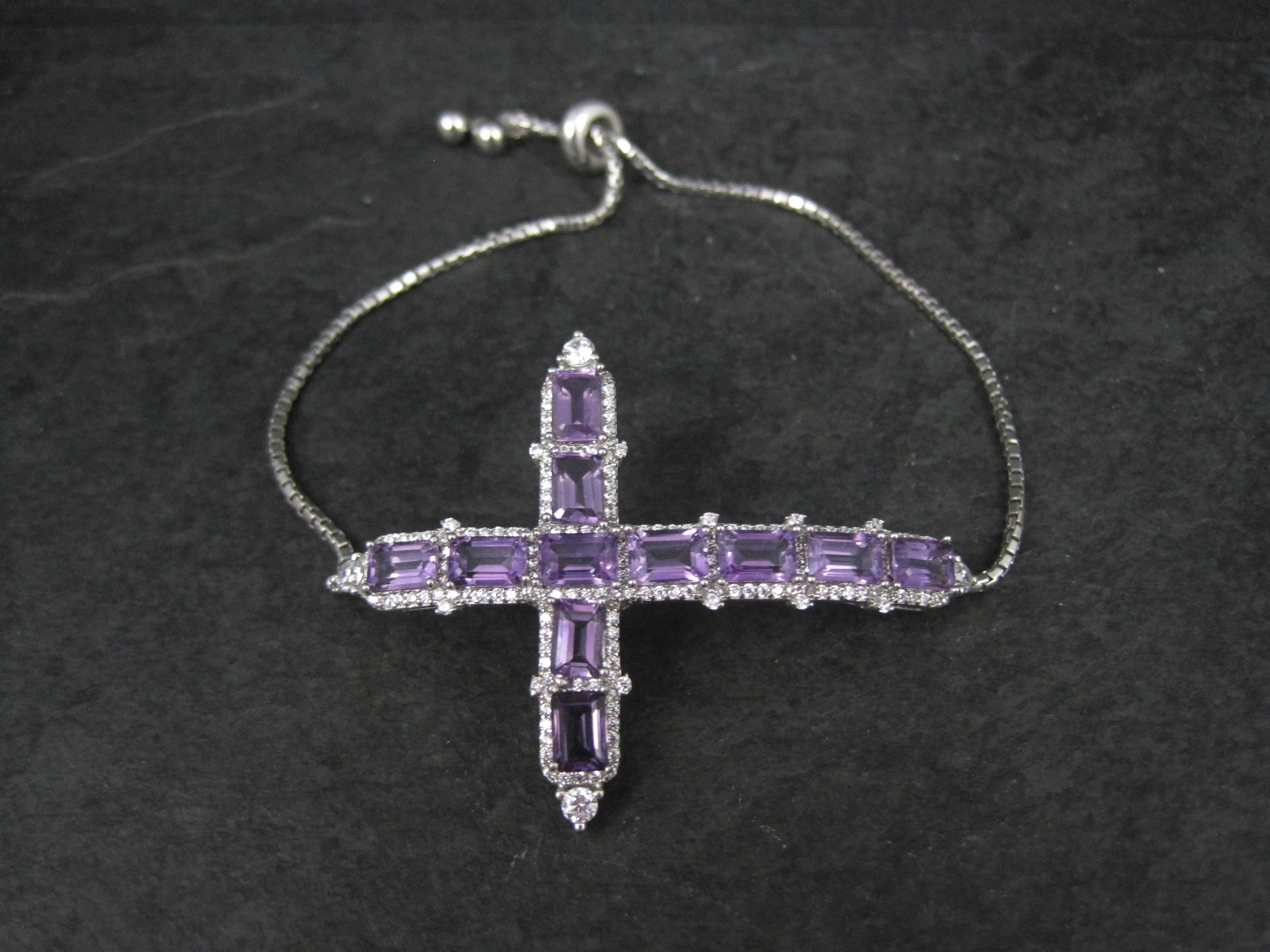 Questo bellissimo bracciale è in argento sterling con chiusura regolabile in stile bolo.
Presenta una splendida croce creata con 11 gemme ametiste 4x6mm dal taglio smeraldo, per un valore stimato di 6,05 carati, e zirconi bianchi.
La croce focale