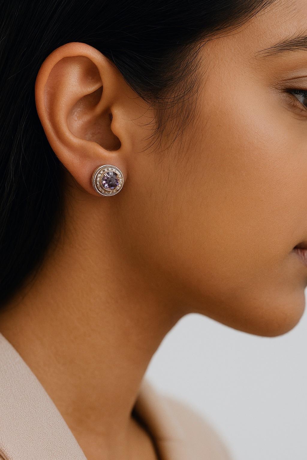 This pair of stud earrings features natural round-cut amethysts, each measuring approximately 6mm in diameter. The gemstones display a rich violet hue with well-defined facets that enhance light dispersion. The round cut maximizes the optical