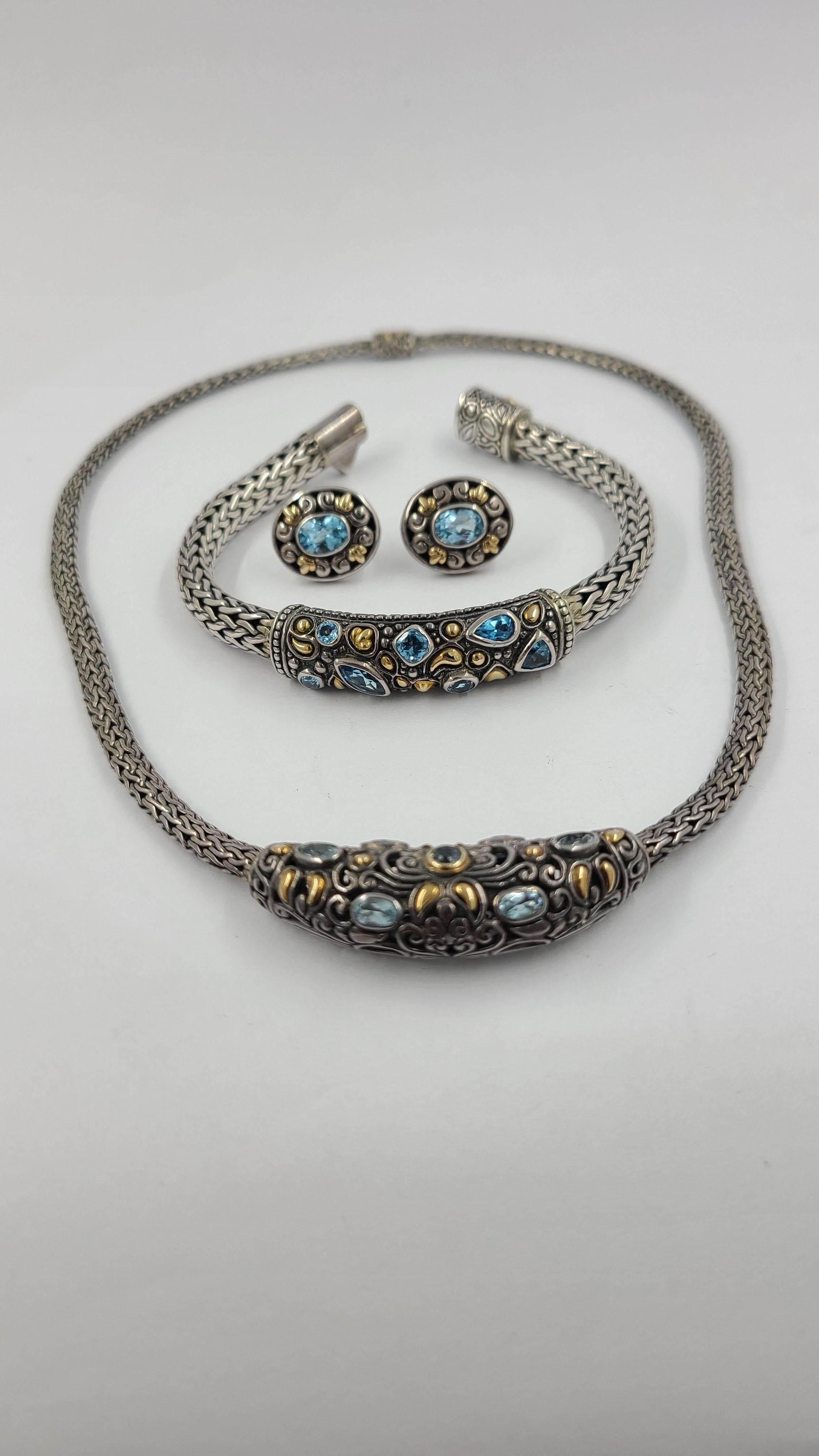 Matched Set of Necklace, Bracelet, & Earrings Crafted in Sterling Silver with 18 Karat Yellow Gold Accents. The Balinese style weave design features a variety of faceted blue topaz shapes bezel set in the front of each piece. The necklace measures