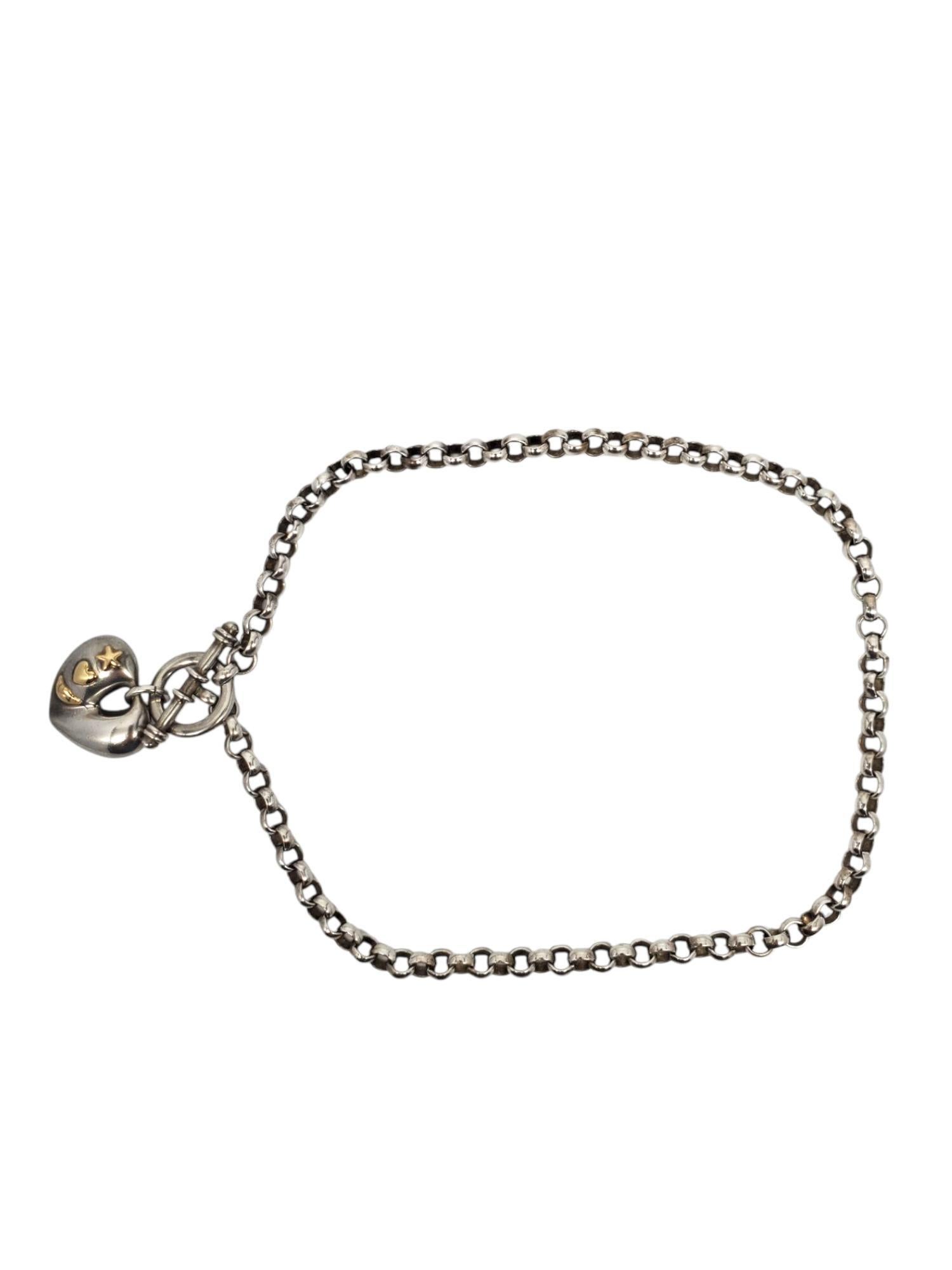 Collana con ciondolo a forma di cuore gonfio in argento sterling e oro giallo 18K 

Questa elegante collana in argento sterling presenta un ciondolo a forma di cuore gonfio con intarsi a stella, cuore e luna in oro 18 carati su una catena rollo con