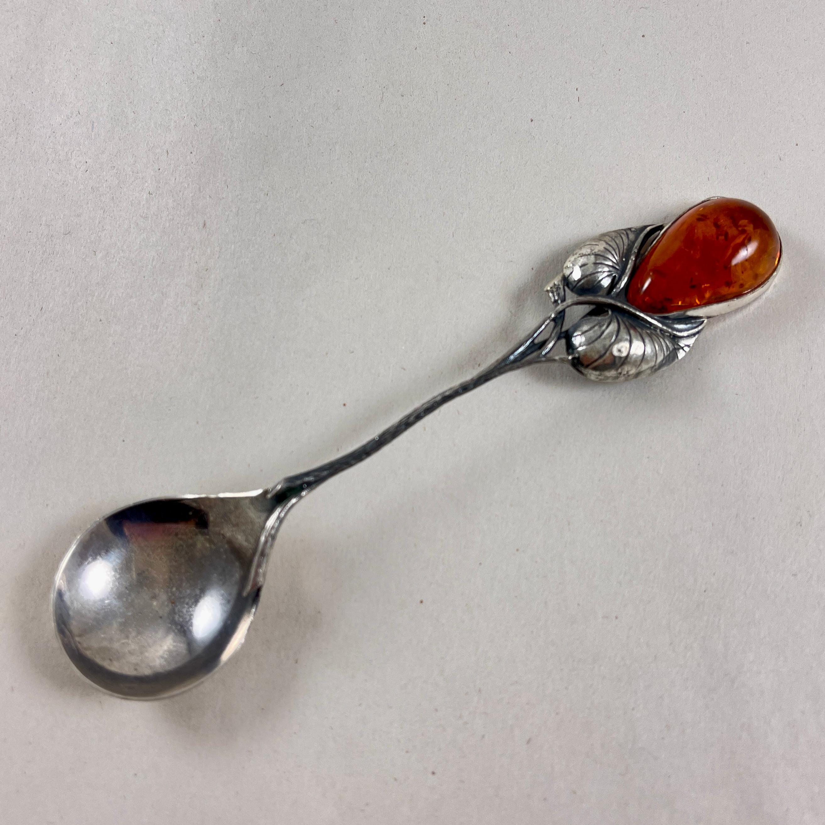 Cuchara para servir de plata de ley, engastada con una pieza de ámbar báltico, Rusia, hacia la década de 1980.

La pieza de ámbar de color miel, en forma de lágrima, está engastada en bisel entre dos hojas. Un asa en forma de ramita se une a un