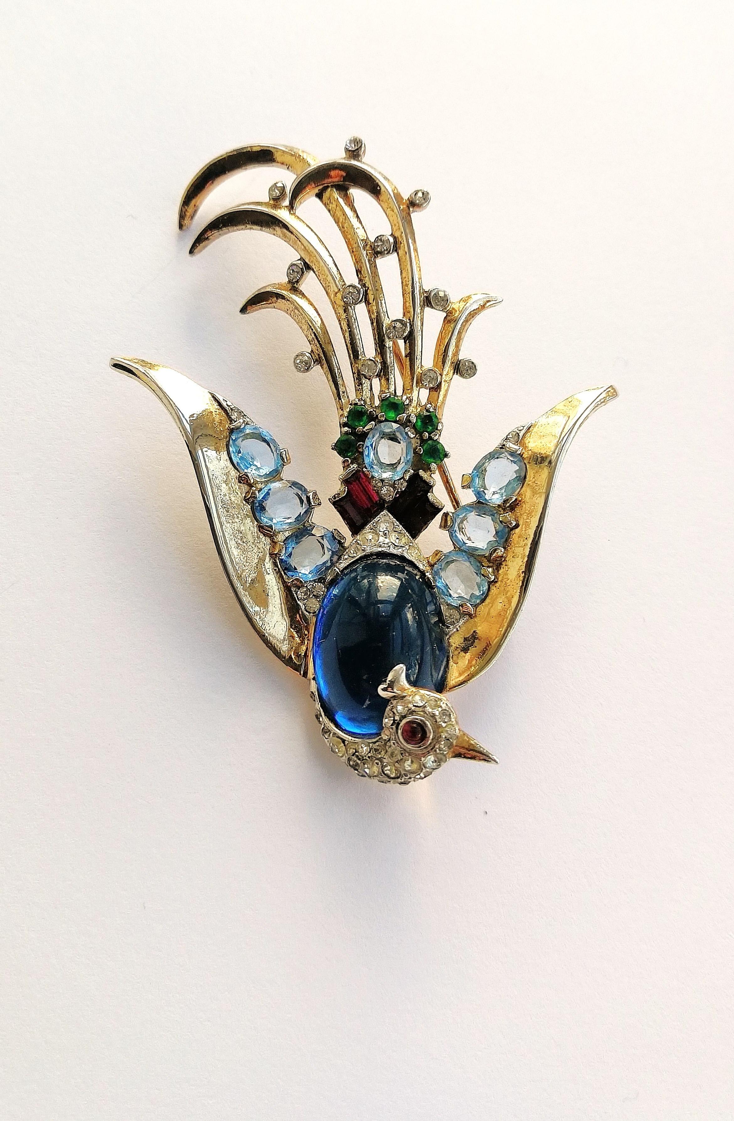 A very beautiful, glamorous and elegant 'cocktail' brooch depicting a swooping bird of paradise, of the highest quality, and made in gilded sterling silver set with a beautiful soft colour combination of coloured pastes and a single paste cabuchon.