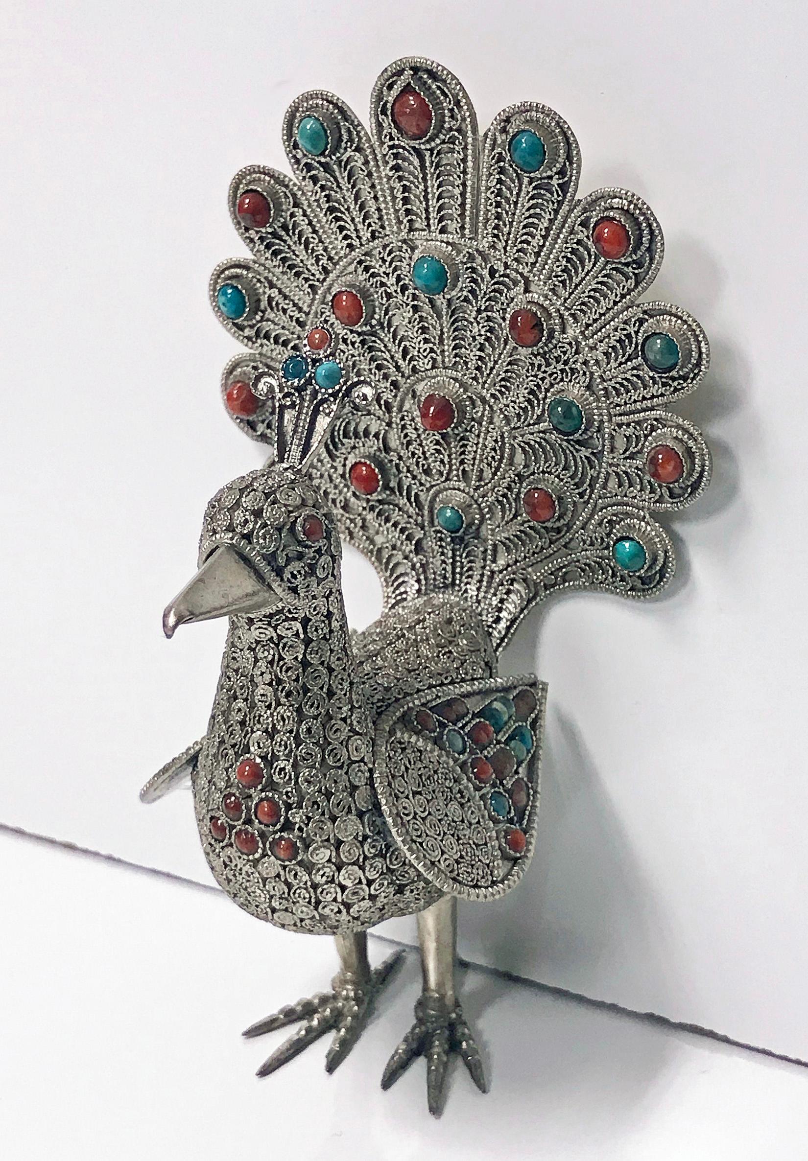 925 Sterling silver and multi-color stone inlay peacock, probably Chinese, circa 1950. The peacock is highly detailed with a Fine silver wire work filigree body, wings, and tail. The silver set with numerous coral and turquoise colored stones. The