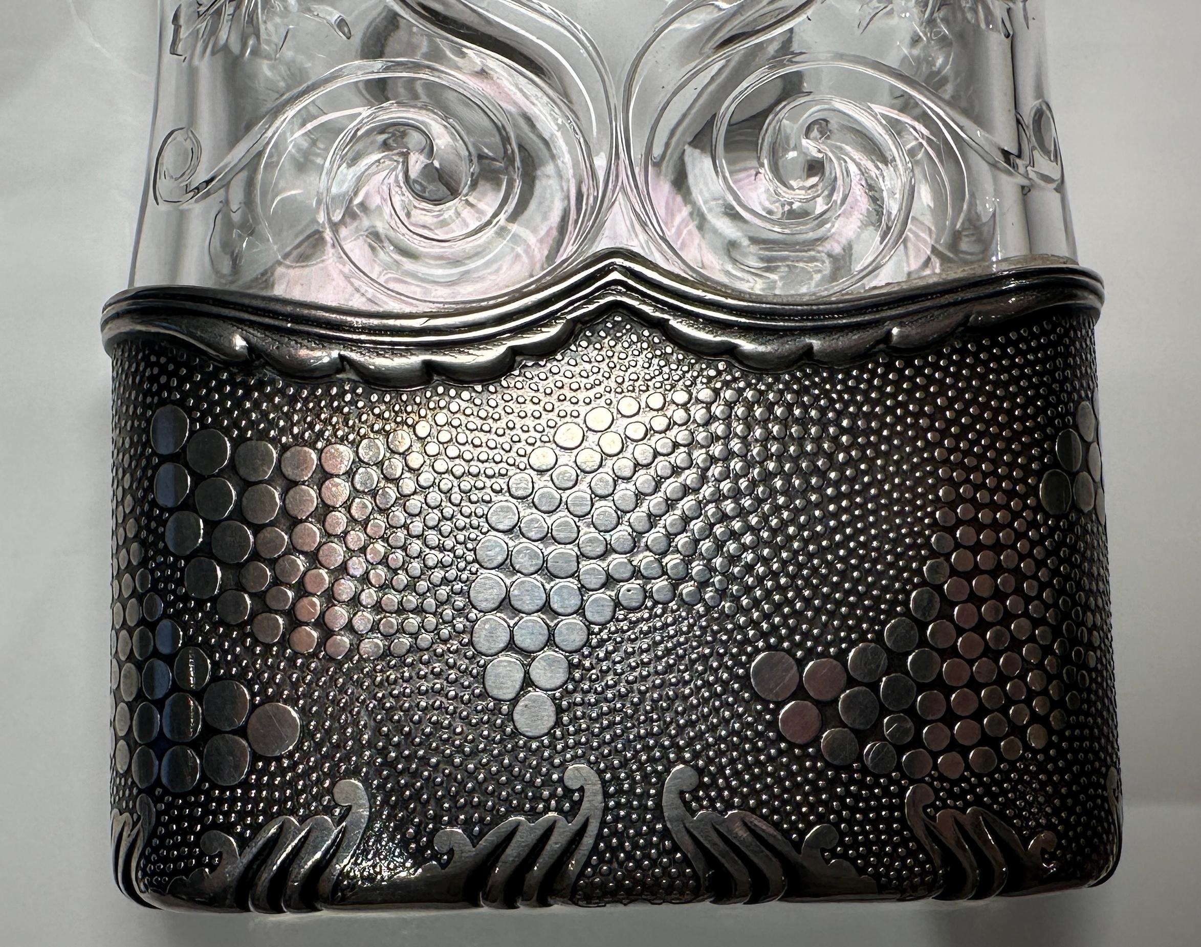 Frasco de plata de ley y cristal, Tiffany & Co., 1893.

Decorado con motivos acuáticos, como olas y burbujas

Fabricado para la Exposición Universal de Chicago de 1893. Con la marca de un globo terráqueo superpuesto a una 