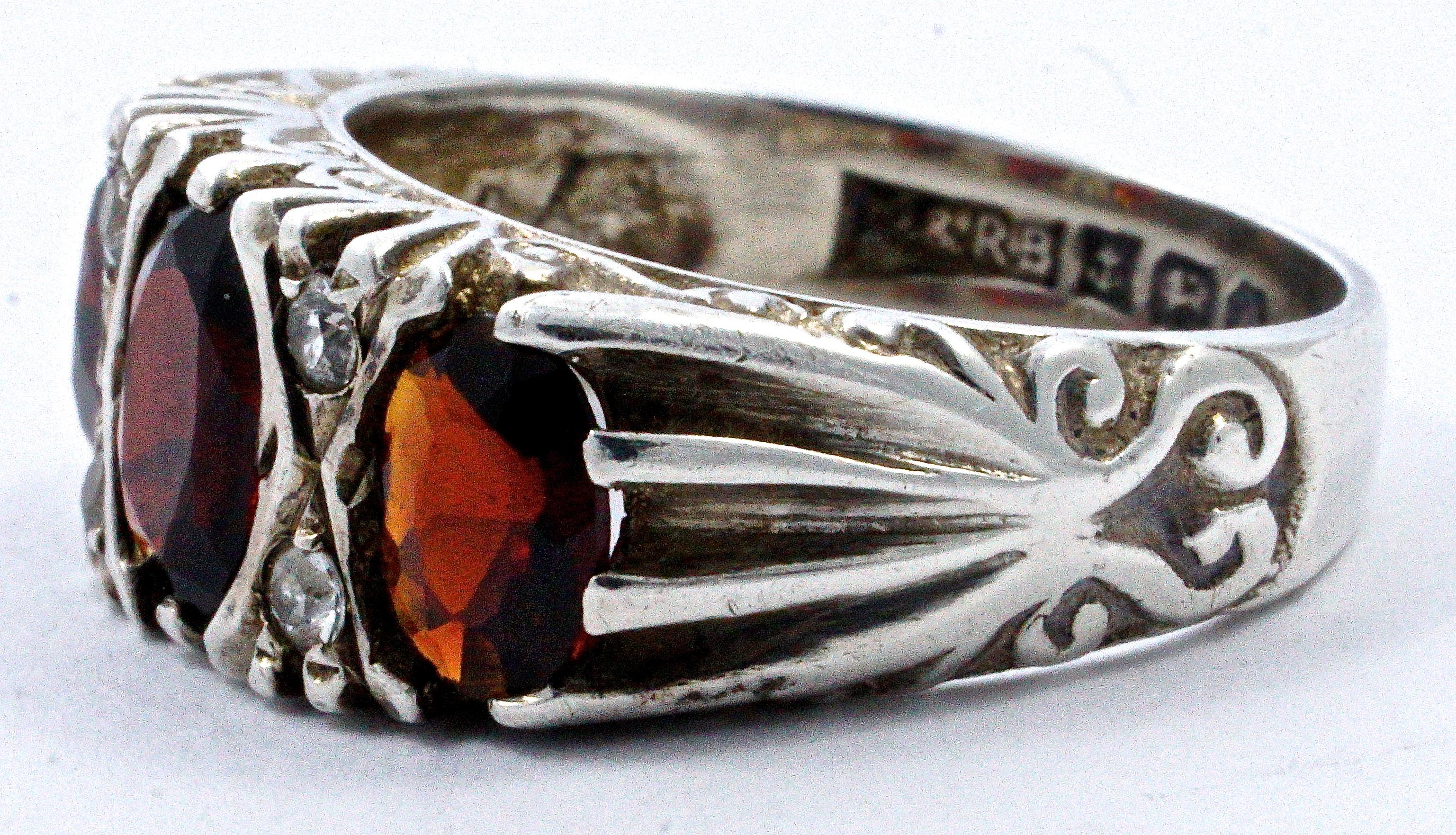 Vintage sterling silver ring featuring three beautiful faceted dark red garnets and four clear rhinestones. A lovely fancy swirl design decorates the setting and shoulders. Ring size UK K / US 5 1/8, and the front measures 1.6cm / .63 inch by