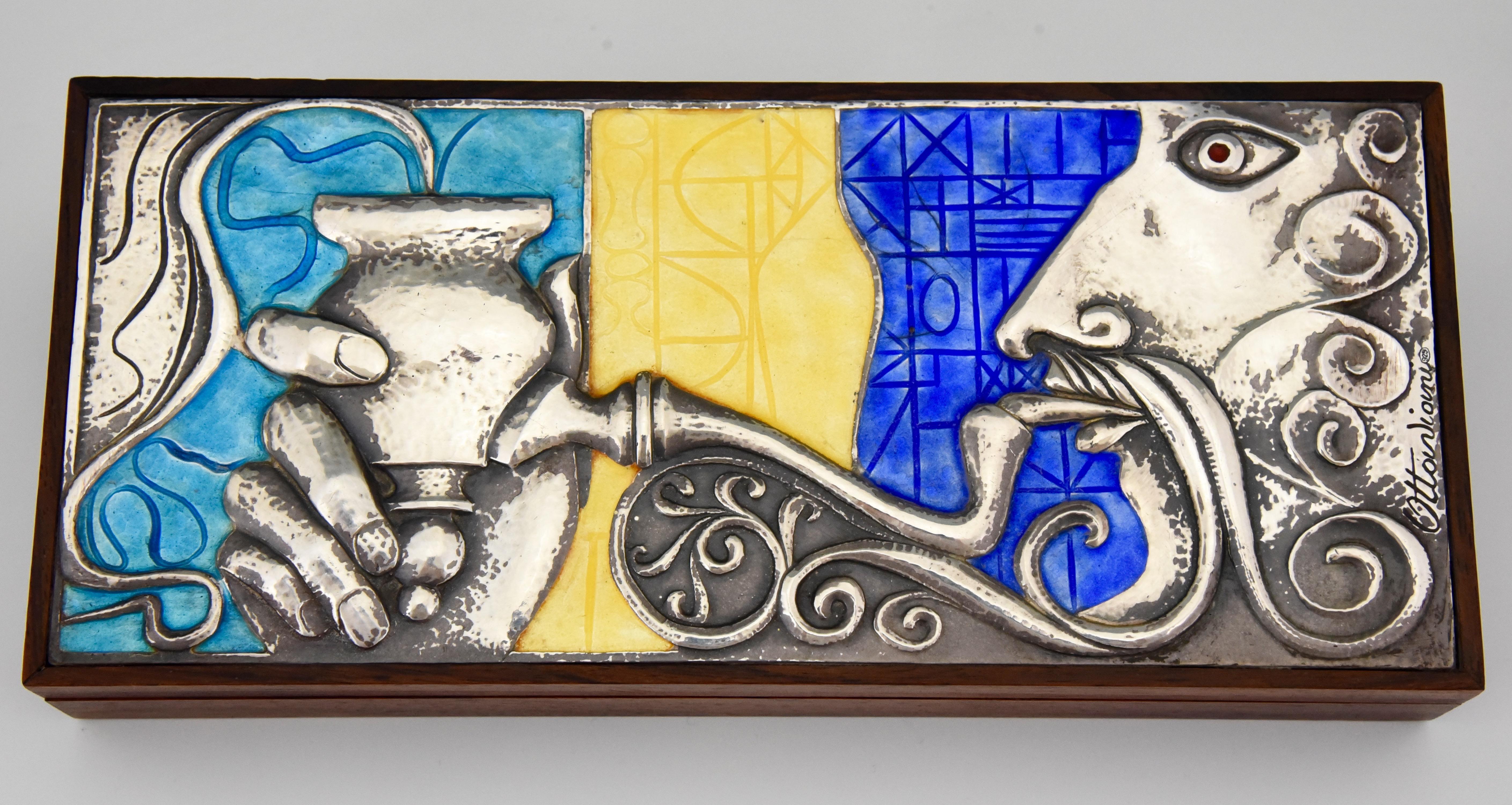 Midcentury sterling silver box with enamel and rosewood picturing a man smoking a water pipe. Beautiful colors for the enamel: blue, yellow and turquoise. Signed by Ottaviani, Italy, 1960.
Ottaviani (1945) is a jewelry and silver firm located in