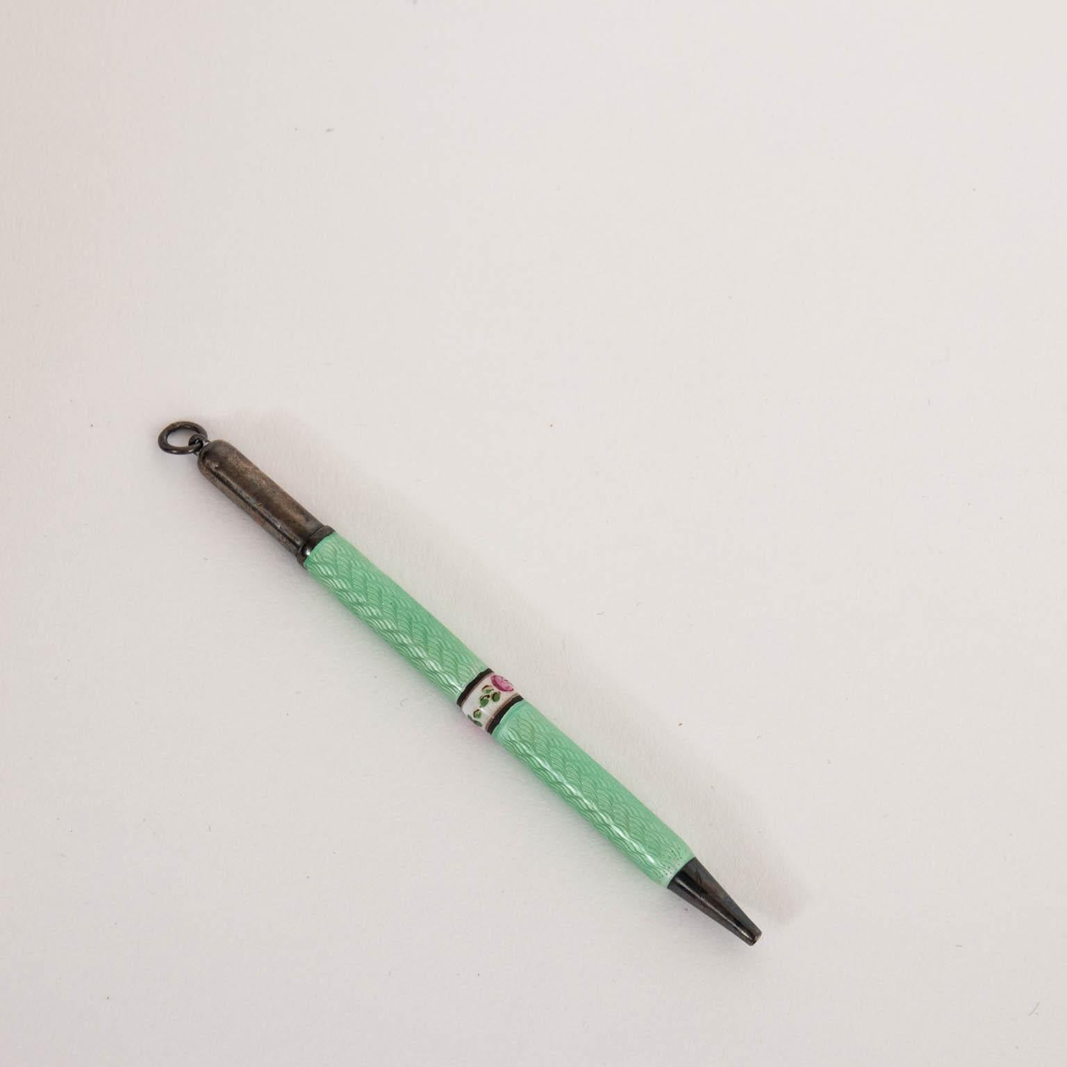 Sterling silver and green enamel pencil, circa 1920s. It features white enamel band in the middle with flower motifs. It weighs 7.8 grams. Please note of wear consistent with age including minor finish loss. Made in the United States. The piece