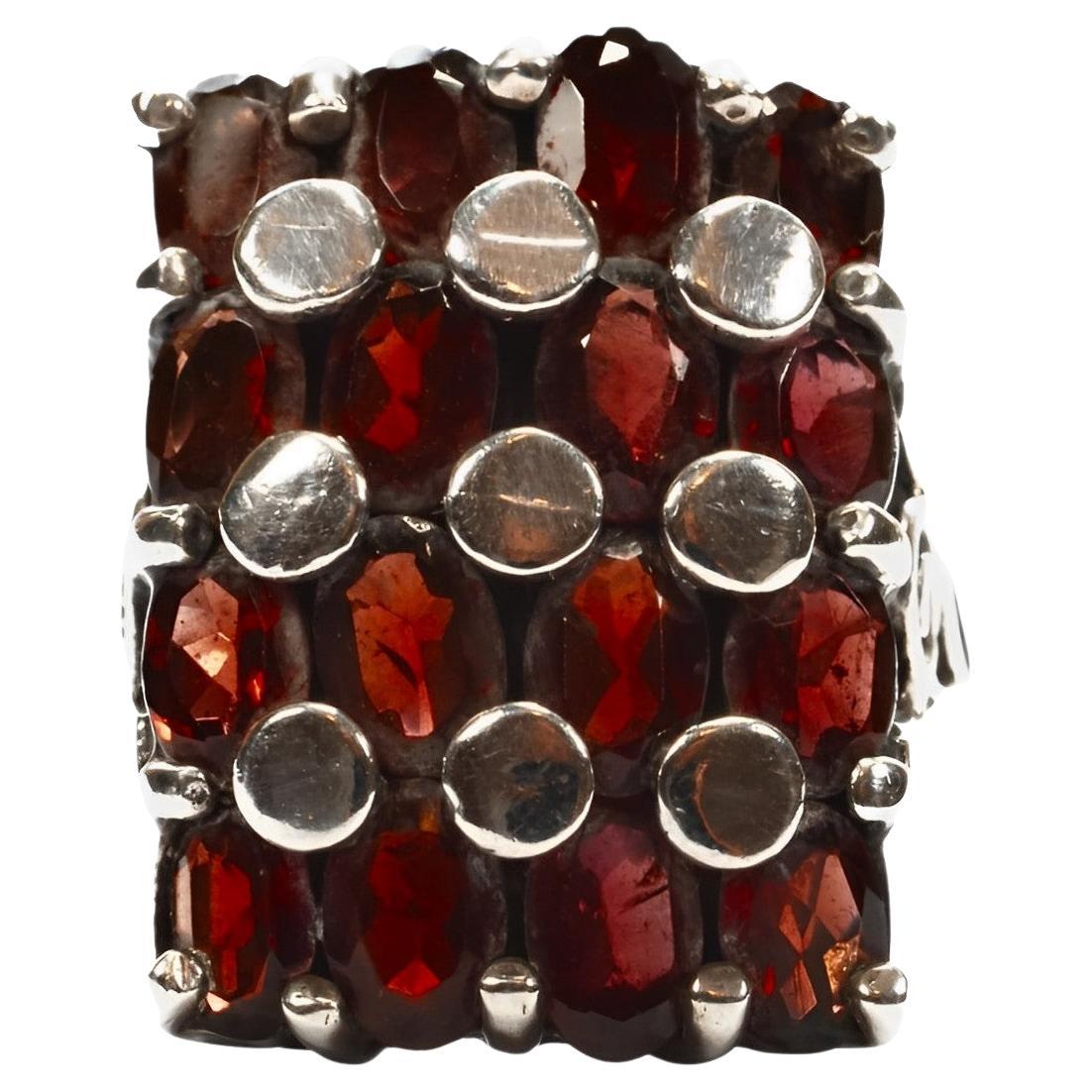 Beautiful sterling silver rectangular ring with sixteen faceted oval garnets. Featuring silver circles, and swirl detail on the shoulders. The front measures 2.3 cm / .9 inch by 1.6 cm / .6 inch. Ring size UK K 1/2, US 5 3/8, inside diameter 1.65 cm