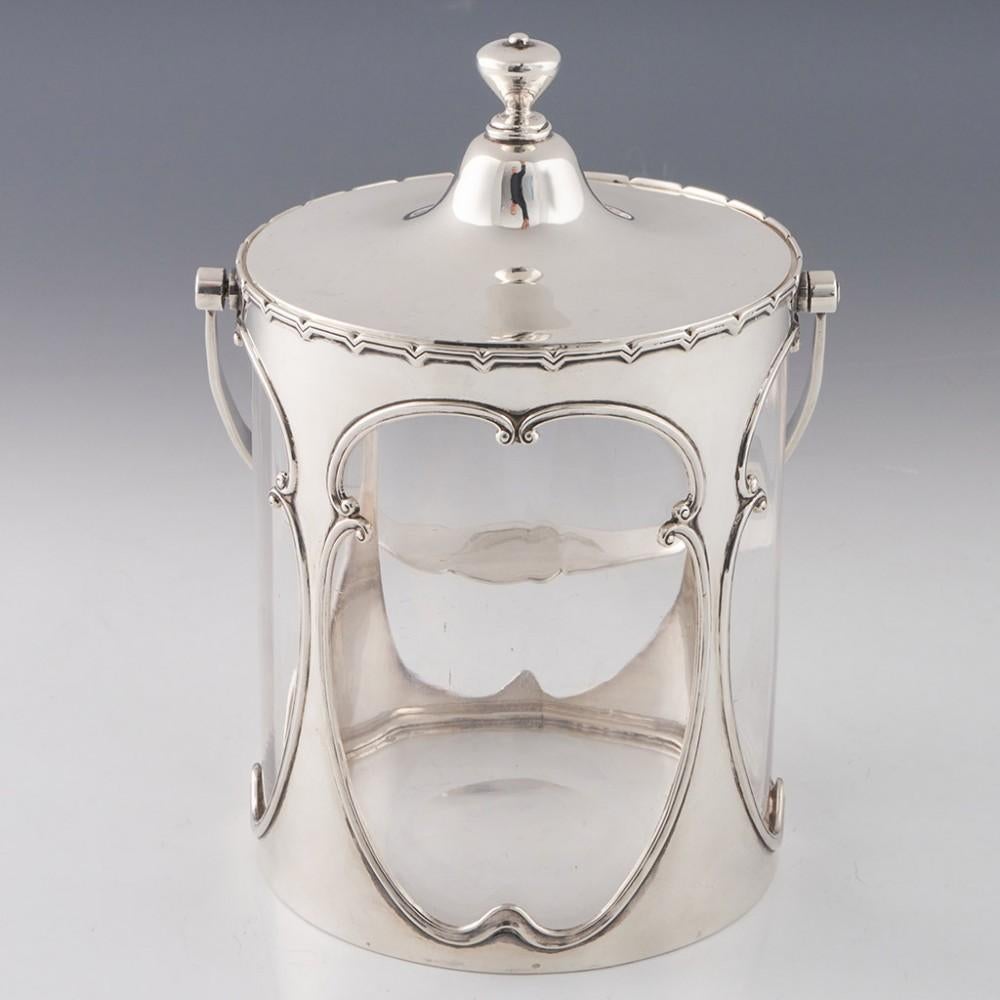 Heading : Sterling silver and glass biscuit barrel
Date : Hallmarked in Birmingham in 1907 for William Henry Sparrow
Period : Edward VII
Origin : Birmingham, England
Decoration : Sterling silver mount and cover, the mount with large scrolled